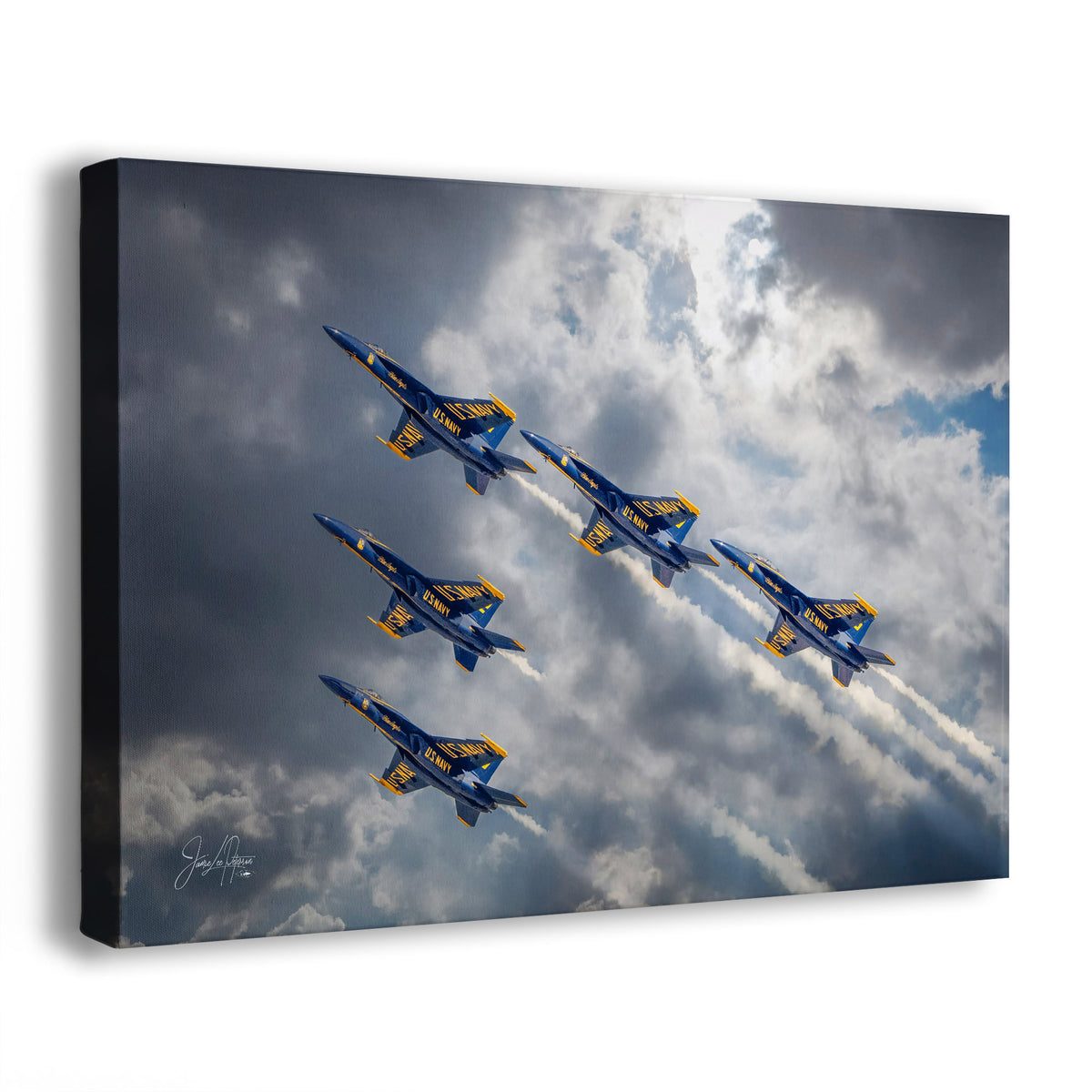 A canvas wall art print showing five blue and yellow jets flying through dramatic clouds, photographed at an angle against a white background.