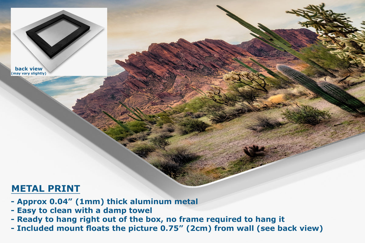 A corner view of an aluminum metal desert landscape wall art print shown at an angle, with a small inset back view and text describing the product as a metal print. The print depicts red rock mountains, cacti, and shrubs under a pale sky.