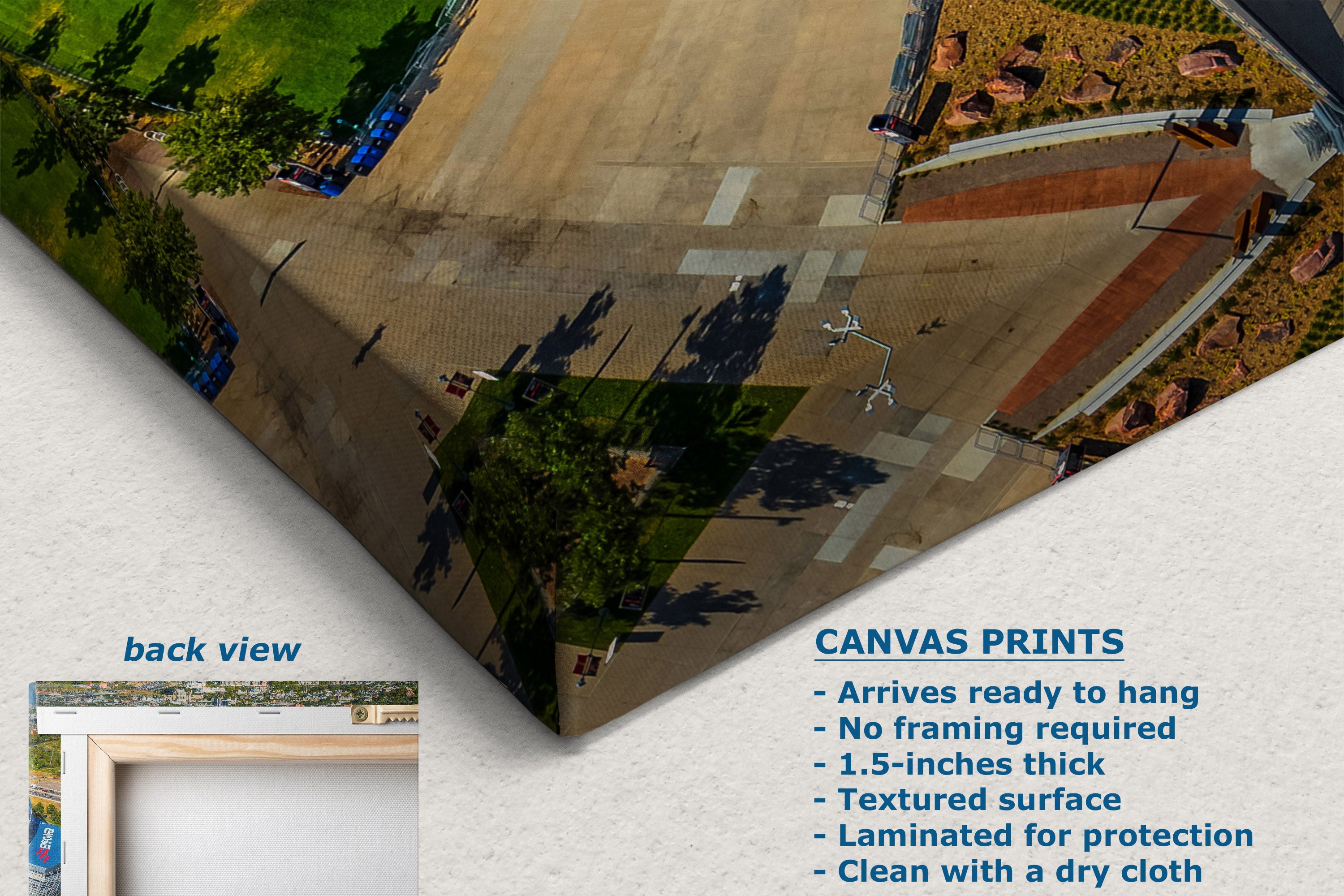 A corner view of a canvas wall art print shown at an angle on a light textured background, displaying an aerial view of a paved plaza with trees and landscaping. The image includes marketing text for canvas prints and a small inset labeled back view.