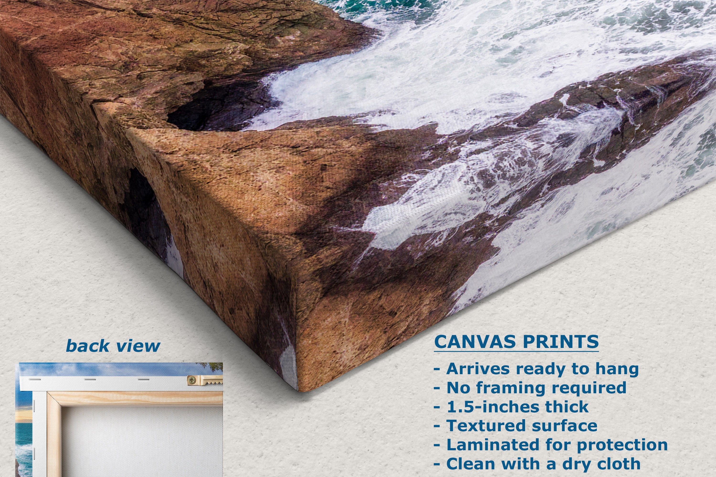 A corner view of a canvas wall art print showing a rocky shoreline with white surf and blue water, displayed at an angle on a light neutral background. Text on the image describes the print features, and a small inset shows the back view of the canvas.