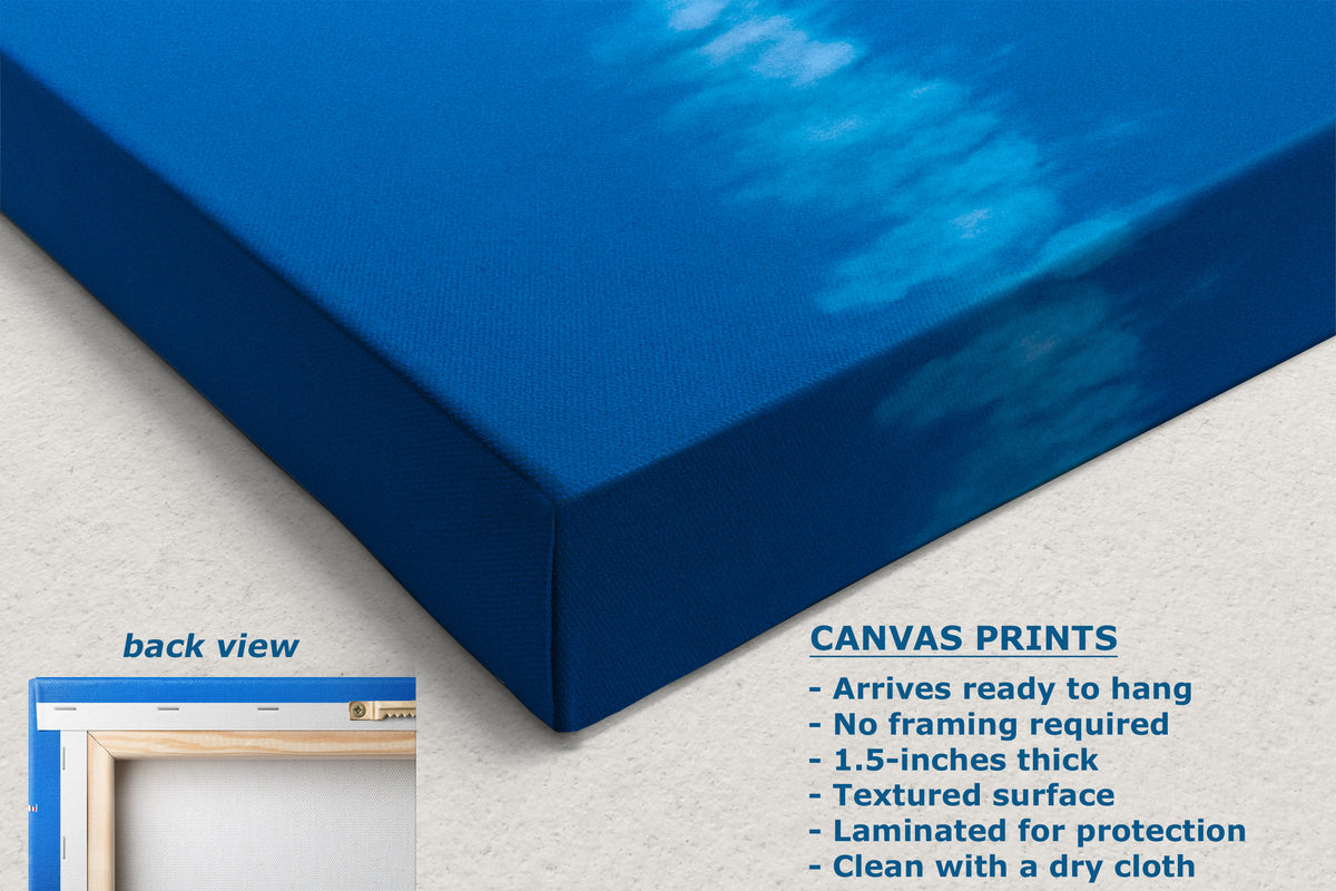 A corner view of a blue canvas wall art print shown at an angle on a light neutral background, with text describing the canvas print features and a small inset labeled back view showing a frame.