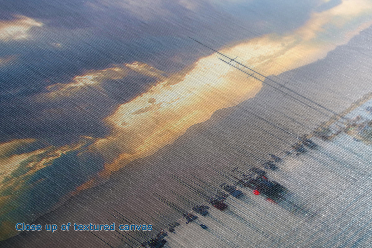 Close-up of a textured canvas print featuring an aerial landscape scene with a golden river or road running through a field under a cloudy sky.