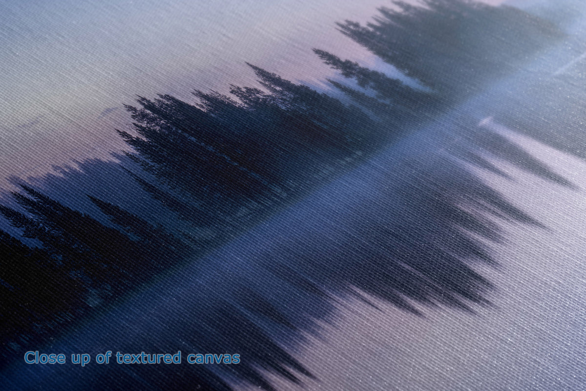 Close-up of a textured canvas print depicting a misty forest scene with dark pine tree silhouettes and a soft blue-purple sky.