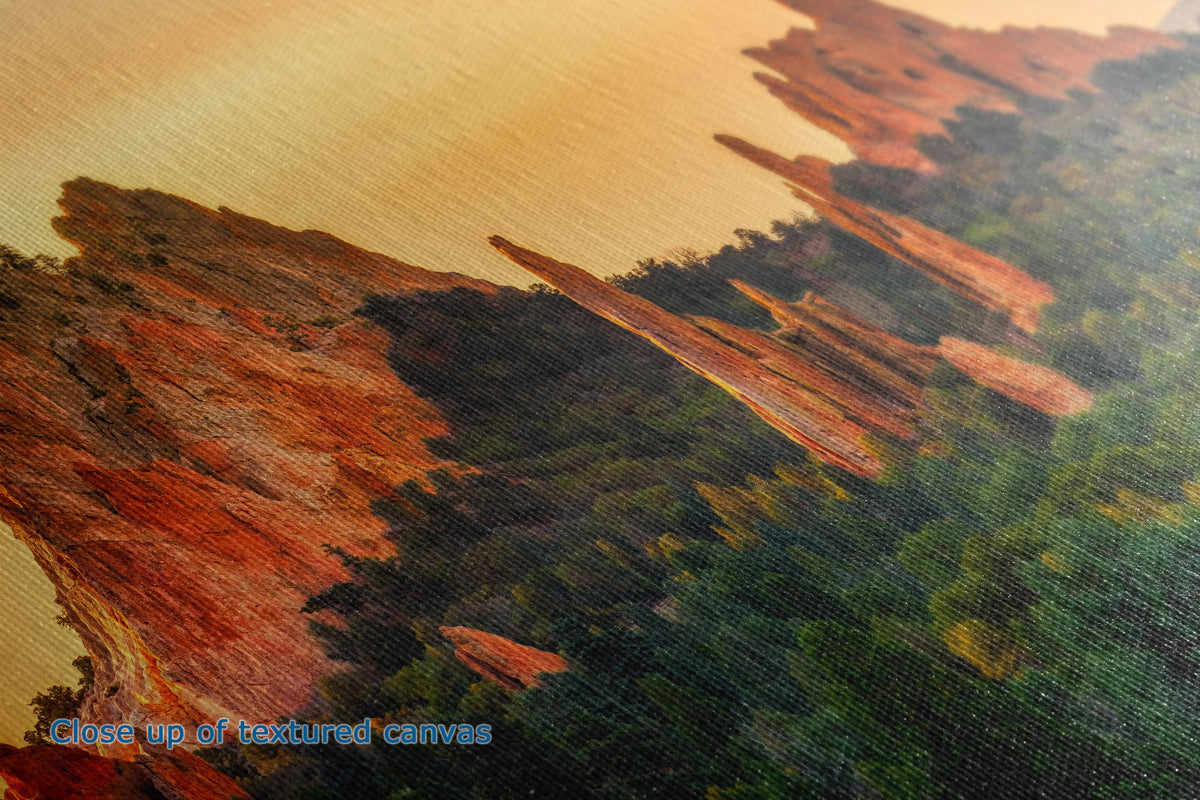 Close-up of the detail and texture of a canvas print depicting a landscape with reddish-brown rock formations and dark green forest under a warm golden sky.