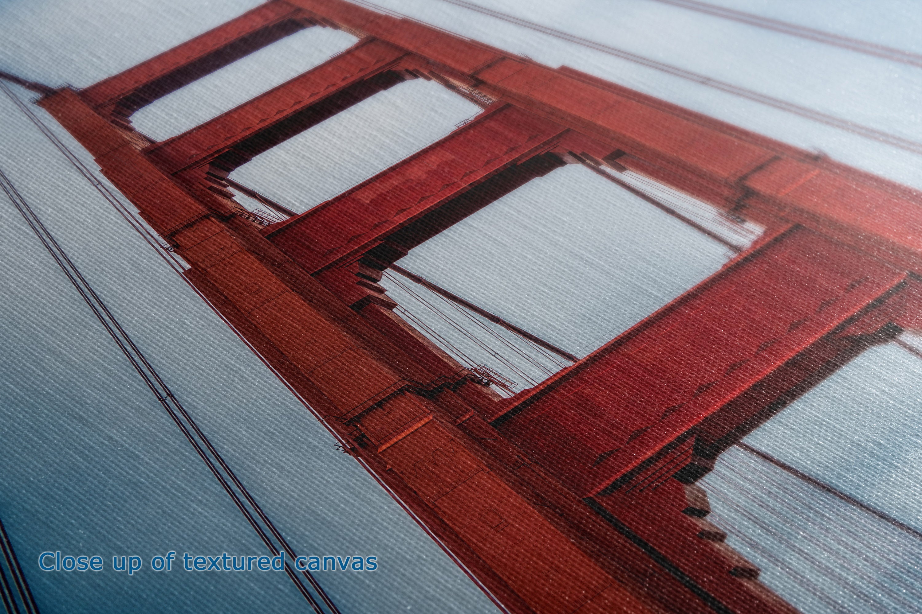 Close-up of a textured canvas print depicting a red-orange bridge structure over a light blue water background, with a small text overlay in the bottom-left corner reading 'Close up of textured canvas'.