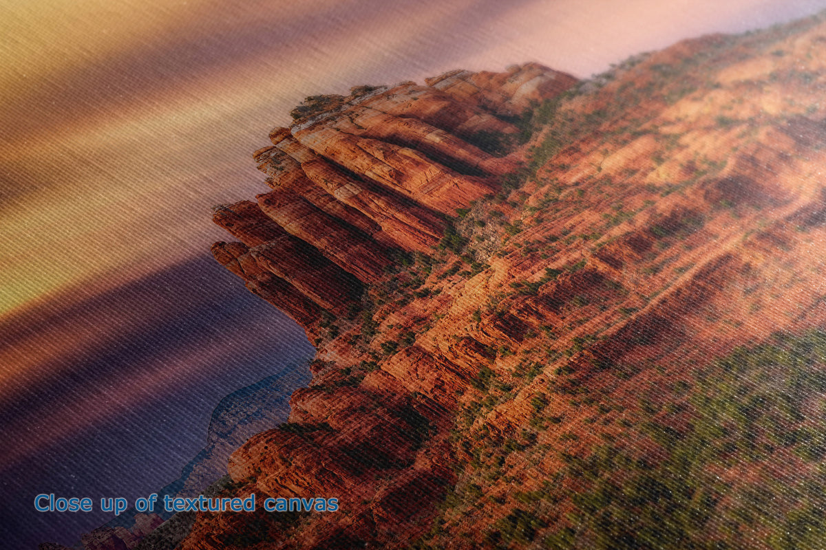 Close-up of a textured canvas print depicting the actual texture and detail of a desert canyon landscape with warm orange and brown rock formations under a golden sky.