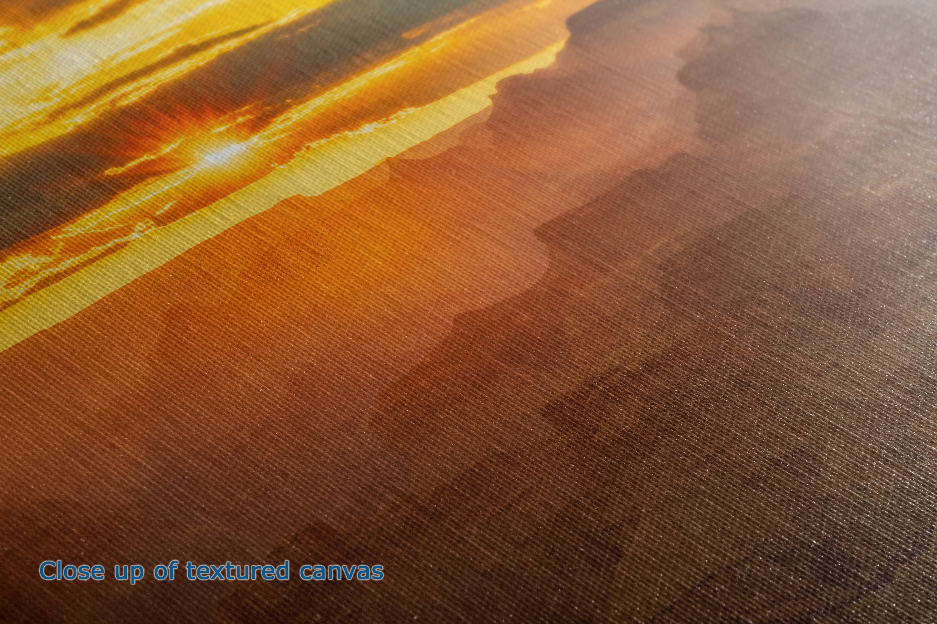 Close-up of a textured canvas print showing a warm sunset landscape with golden yellow, orange, and brown tones, with the text 'Close up of textured canvas' in the lower-left corner.