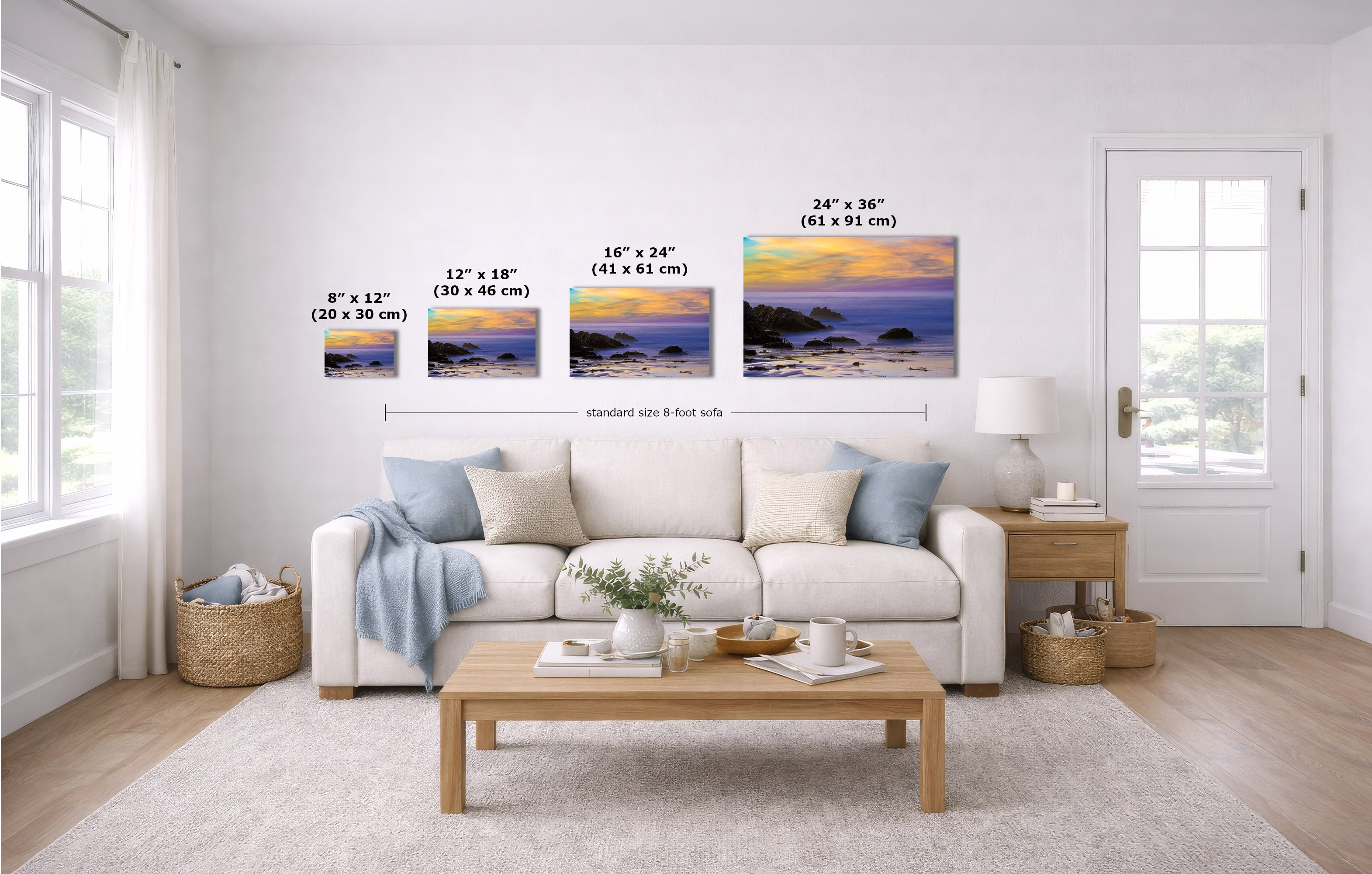 A staged living room with a white sofa, coffee table, and wall-mounted framed art. The product being shown is the set of four landscape wall prints, each labeled with dimensions (8 x 12, 12 x 18, 16 x 24, 24 x 36 inches).