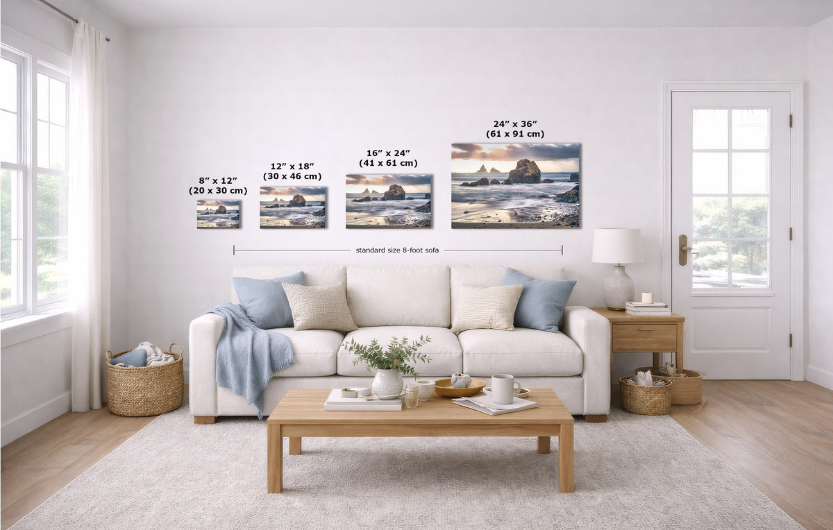 A staged living room shows four coastal landscape prints mounted on a white wall above a sofa. The image includes size labels for each print and a note about standard 8-foot wall spacing.