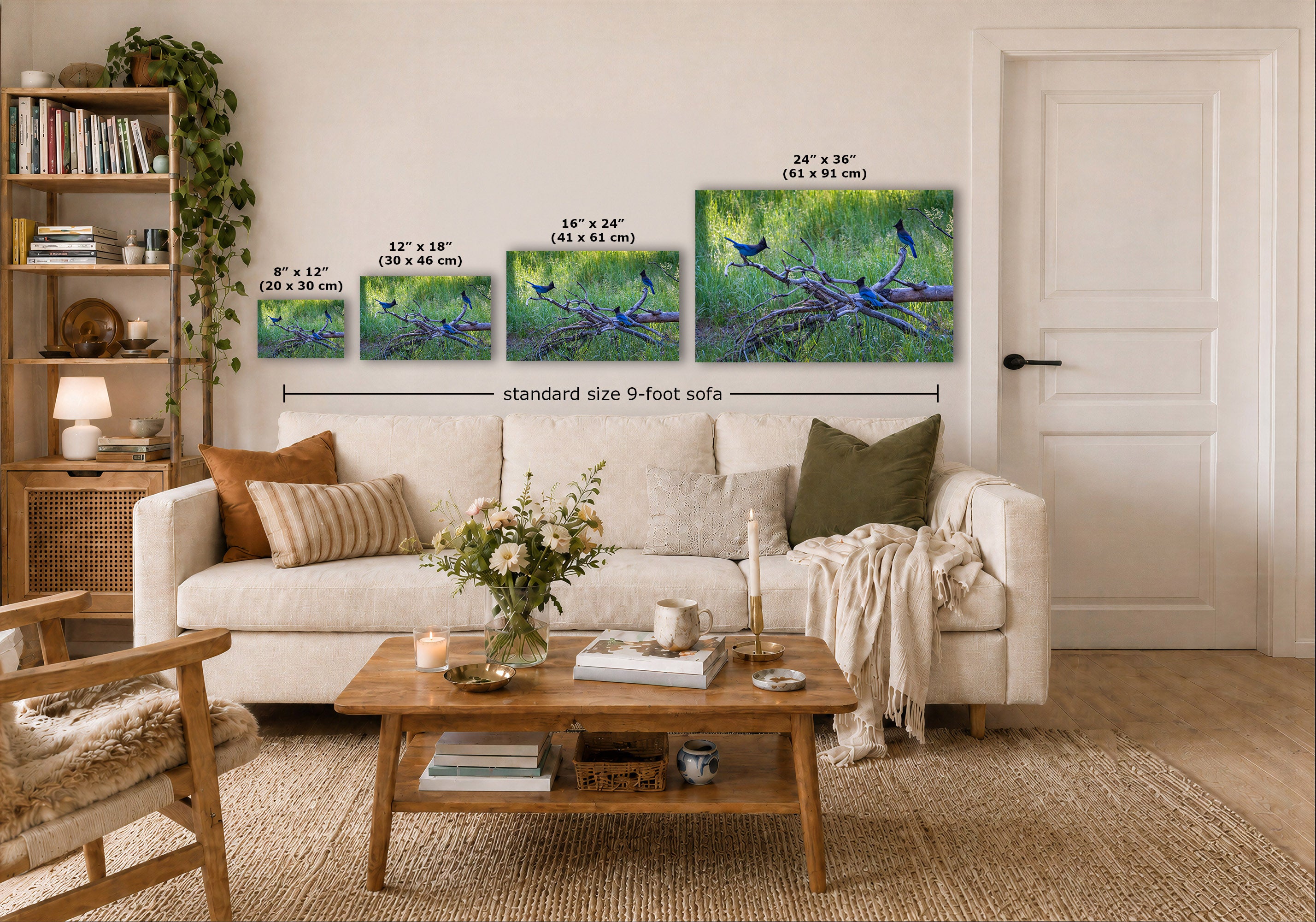 A staged living room shows a set of four wall art prints above a white sofa, each with size text overlaid in inches and centimeters. The artwork depicts blue birds perched on branches in green and blue scenery.