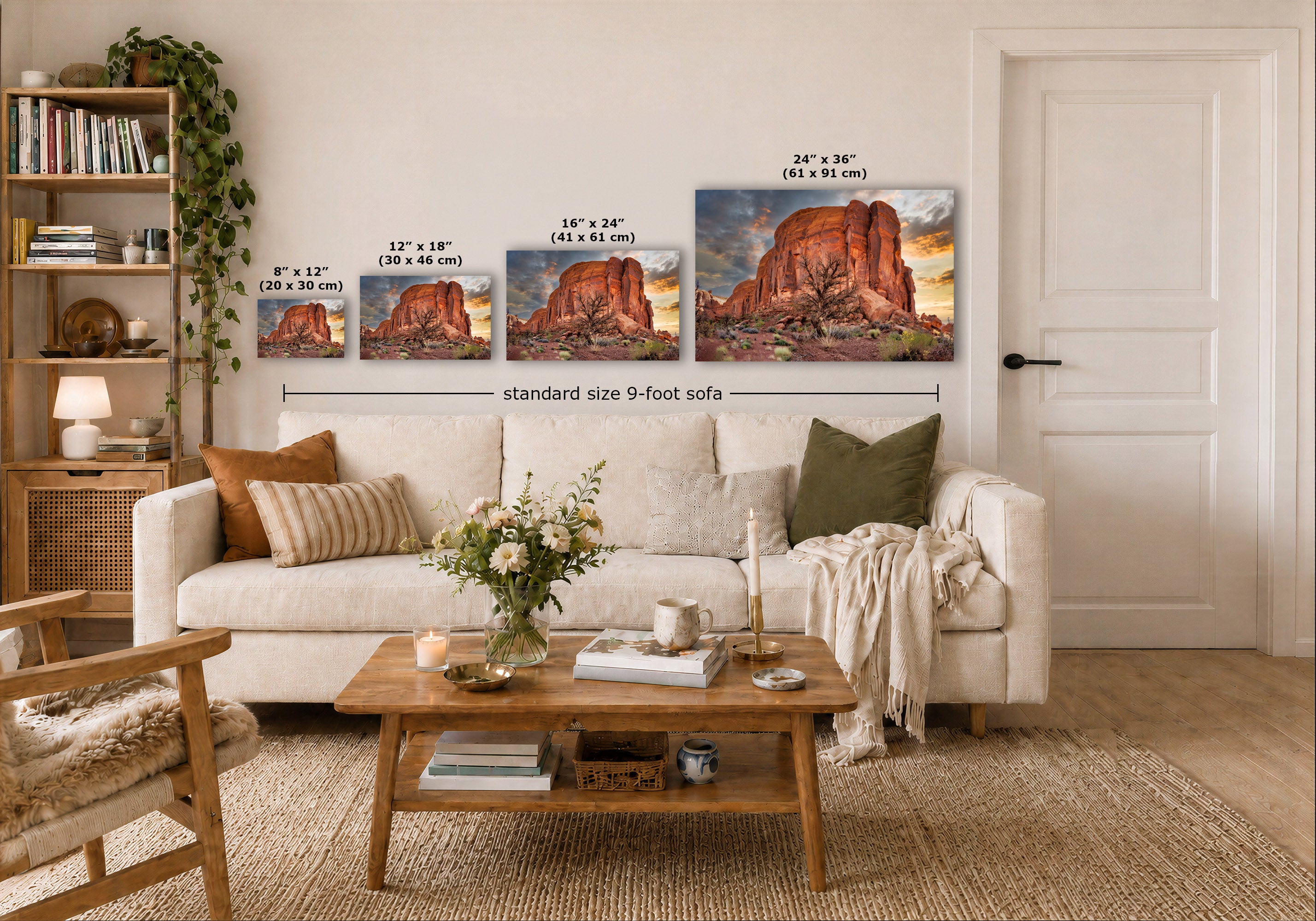 A styled living room showing four landscape art prints above a white sofa, with size labels overlaid for each print and a note reading 'standard size 9-foot sofa.' The scene includes a wooden coffee table, books, a chair, and a door in a real interior environment.