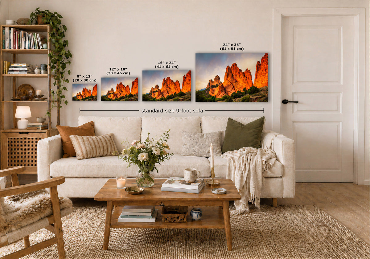 A staged living room shows a set of four wall art prints above a sofa, each depicting a vivid orange and red desert canyon landscape. White dimension labels and text indicate the sizes of the prints, including a larger 24 x 36 option, with a note for a standard size 9-foot sofa.