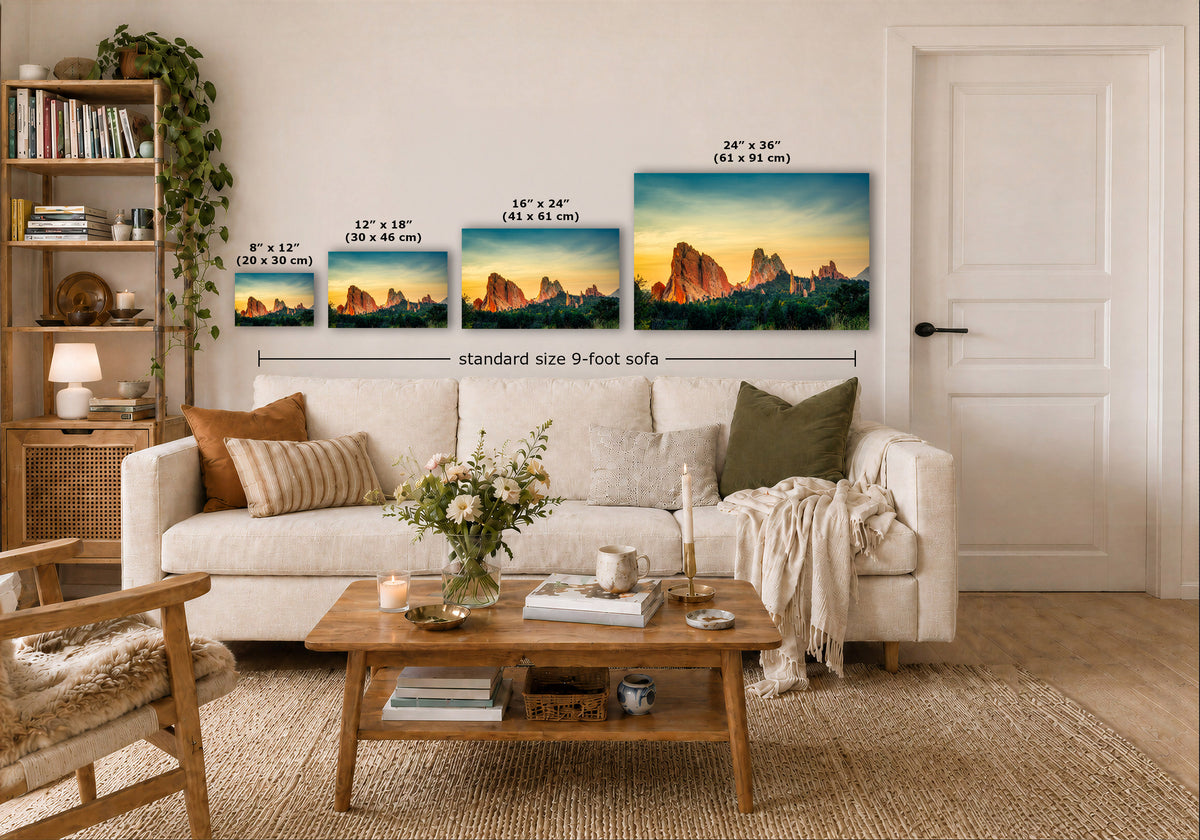 A staged living room shows a white sofa with pillows, a wooden coffee table, shelving, and a door, with four mountain landscape prints mounted above the sofa. Small size labels and a 'standard size 9-foot sofa' measurement overlay indicate the wall art dimensions.