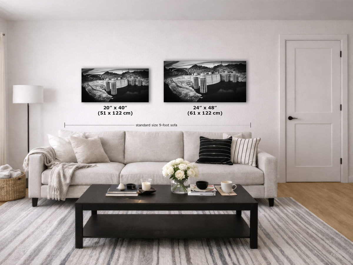 A styled living room showing two black-and-white framed wall art prints above a light sofa, with size labels overlaid: 20 x 40 inches and 24 x 48 inches. The room includes a coffee table, rug, lamp, door, and decorative flowers.