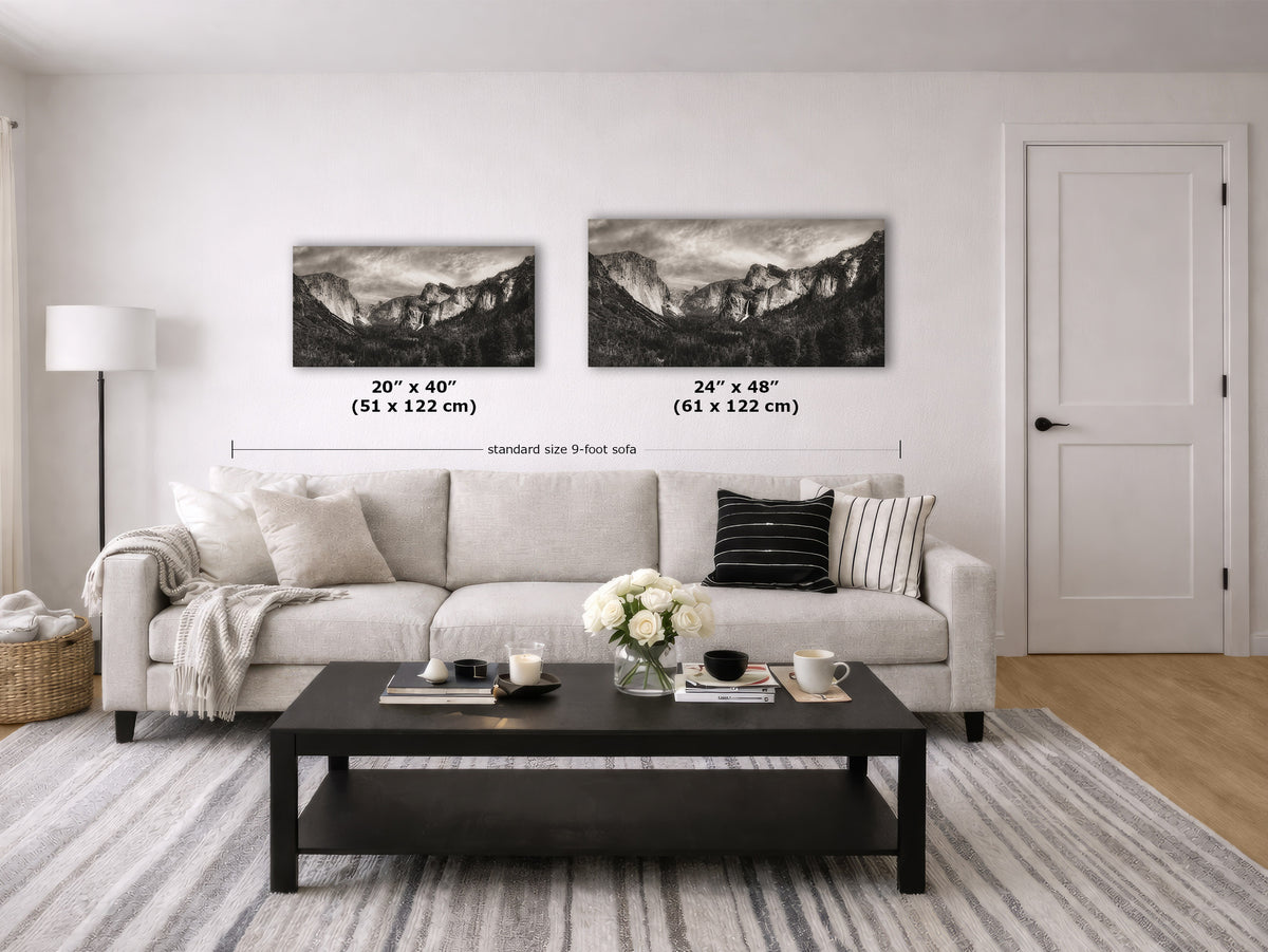 A styled living room showing two black and white mountain landscape wall art prints above a light beige sofa. The image includes size labels for the prints: 20" x 40" (51 x 122 cm) and 24" x 48" (61 x 122 cm).