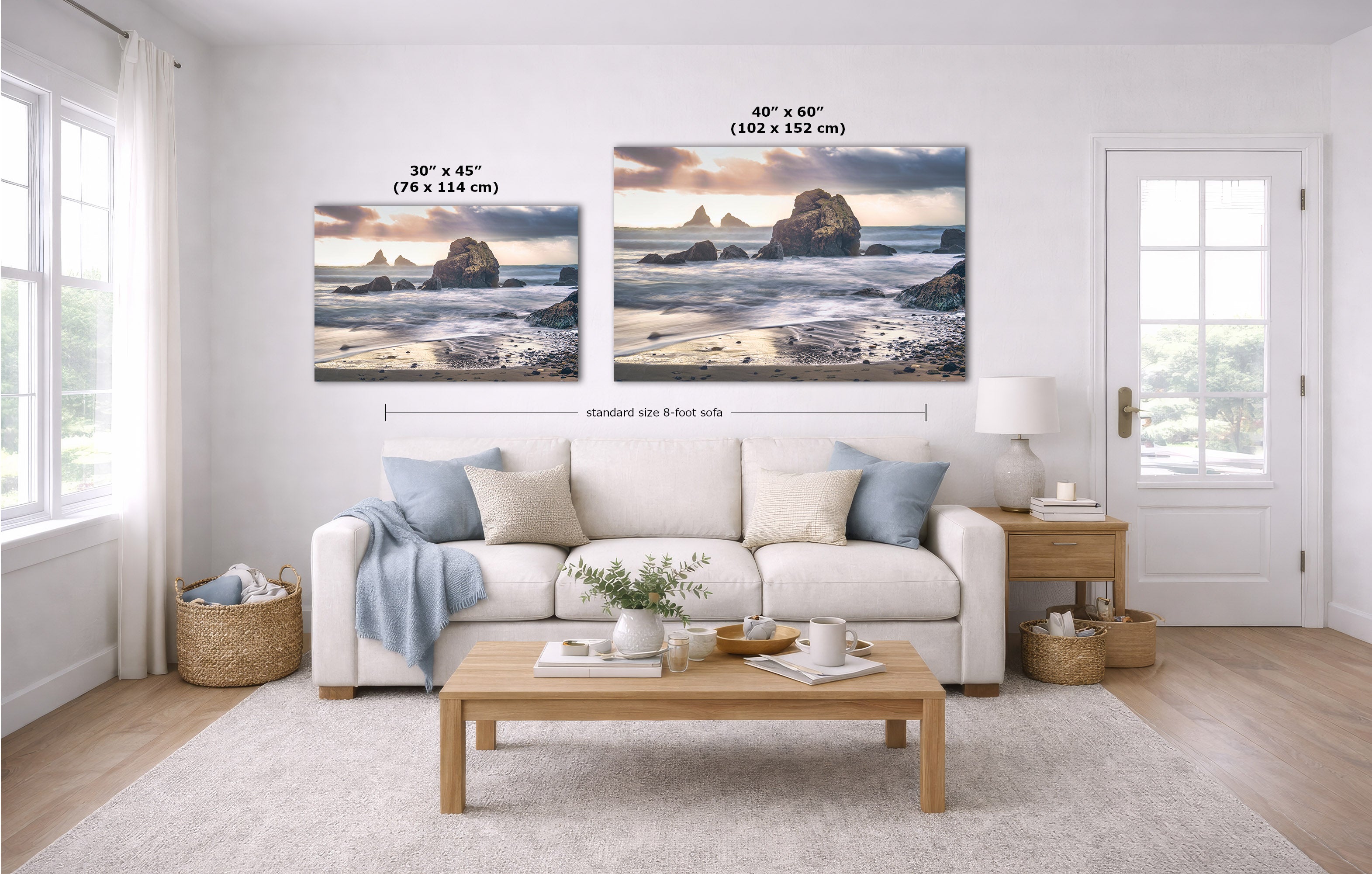 A styled living room showing two coastal landscape wall art prints above a white sofa, with size labels and dimension lines indicating 30 x 45 inches and 40 x 60 inches. The room includes a light wood coffee table, beige rug, side table, lamp, and windows.