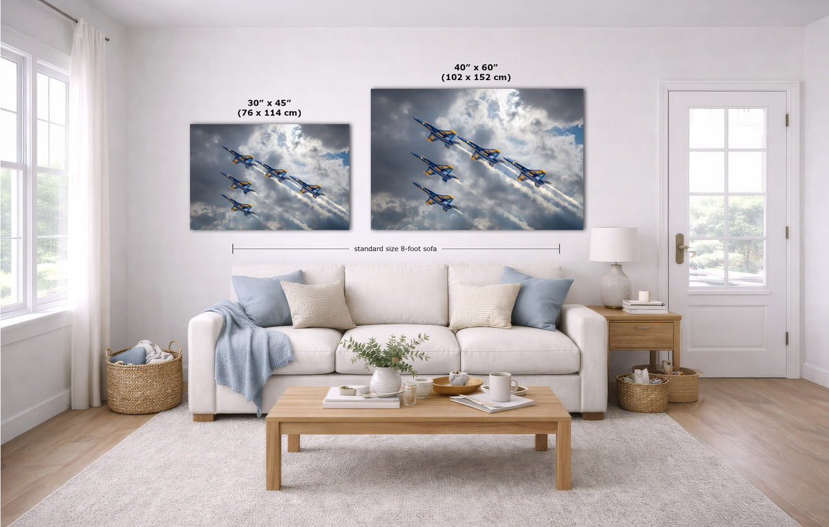 A staged living room shows two wall art prints above a white sofa. The prints depict blue fighter jets flying through dramatic clouds.