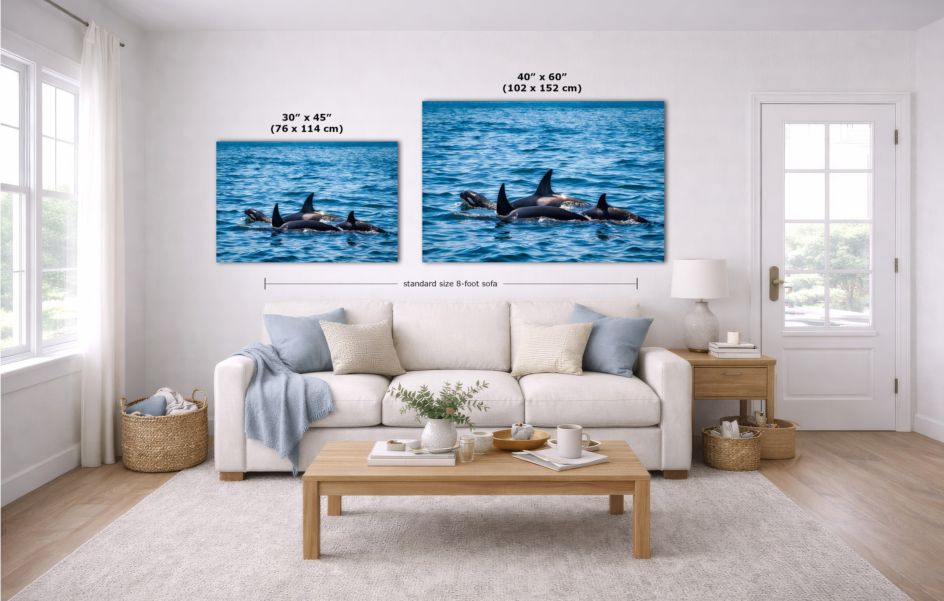 A staged living room shows two canvas wall art prints above a white sofa. The prints depict blue ocean water with orcas surfacing.