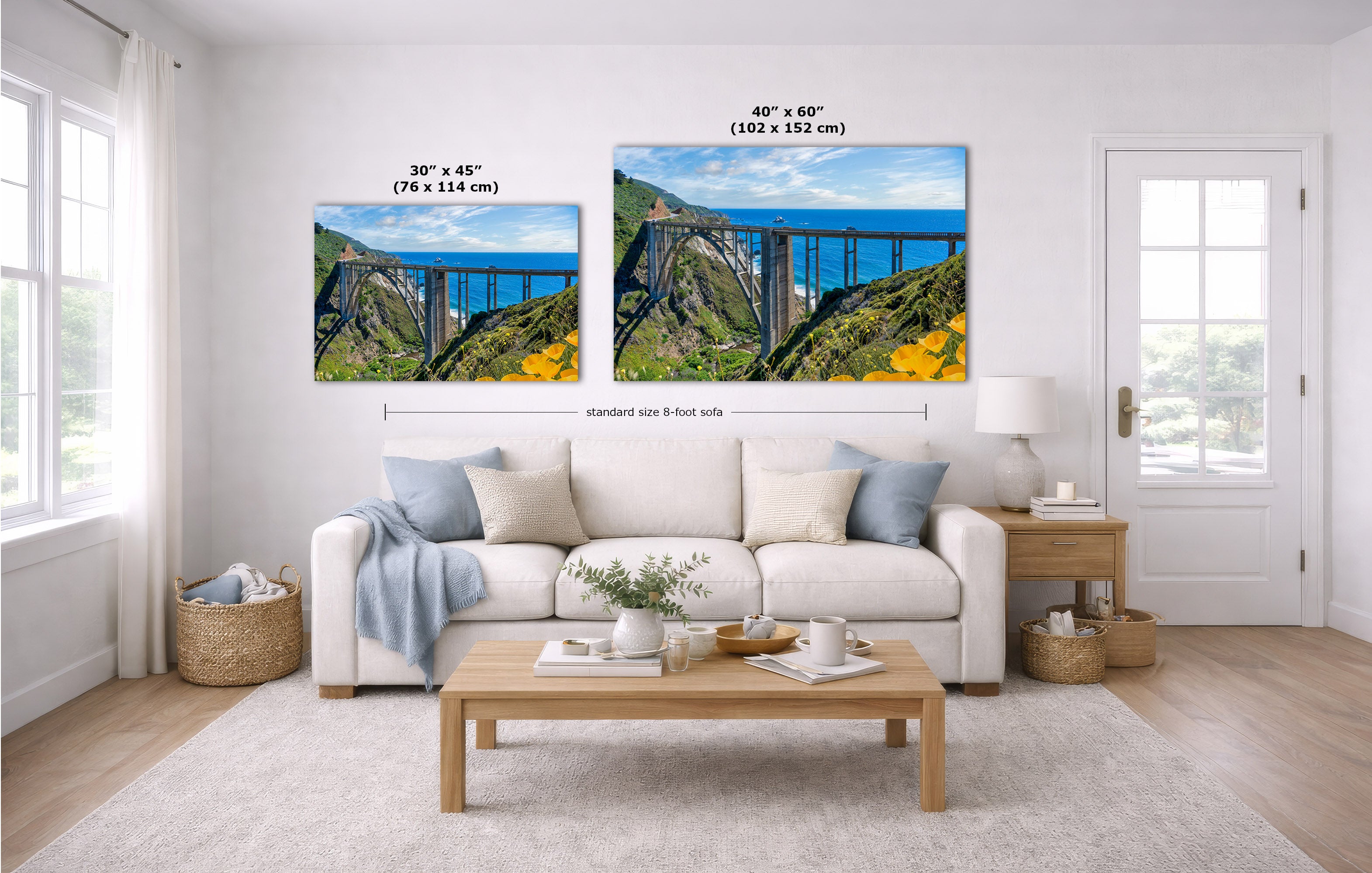 A staged living room shows two wall art prints above a white sofa. The prints depict a blue sky, a bridge, green hills, and yellow flowers.