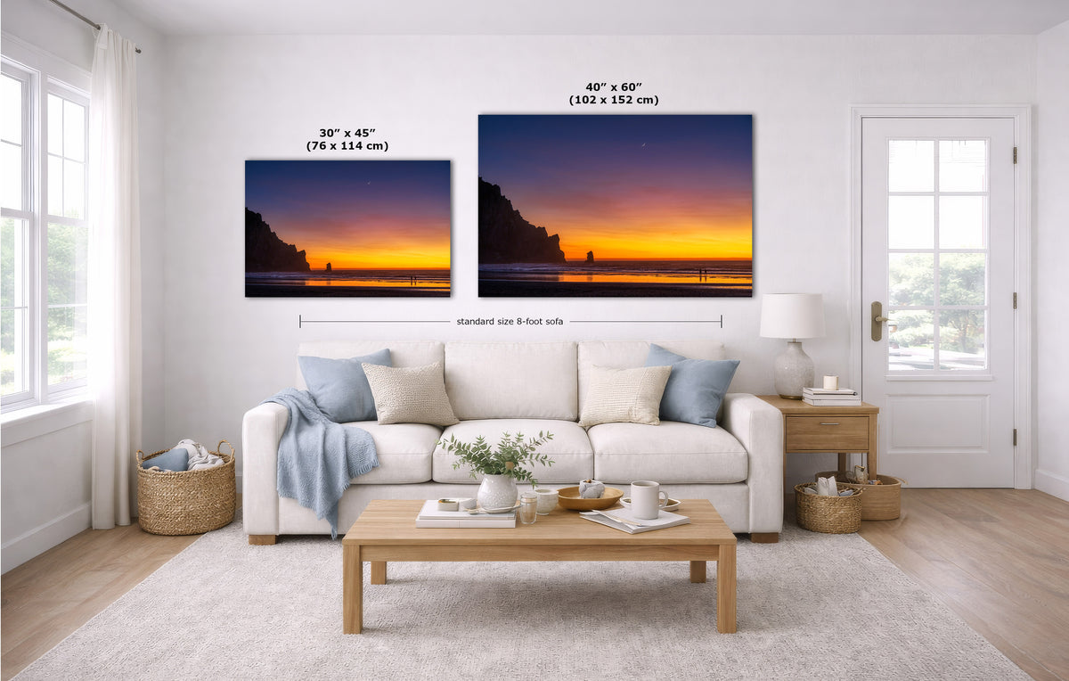 A staged living room with a white sofa, coffee table, and two framed sunset wall art prints above the couch. The prints show cliff silhouettes against orange and purple skies, with size labels and dimension lines overlaid to indicate dimensions.