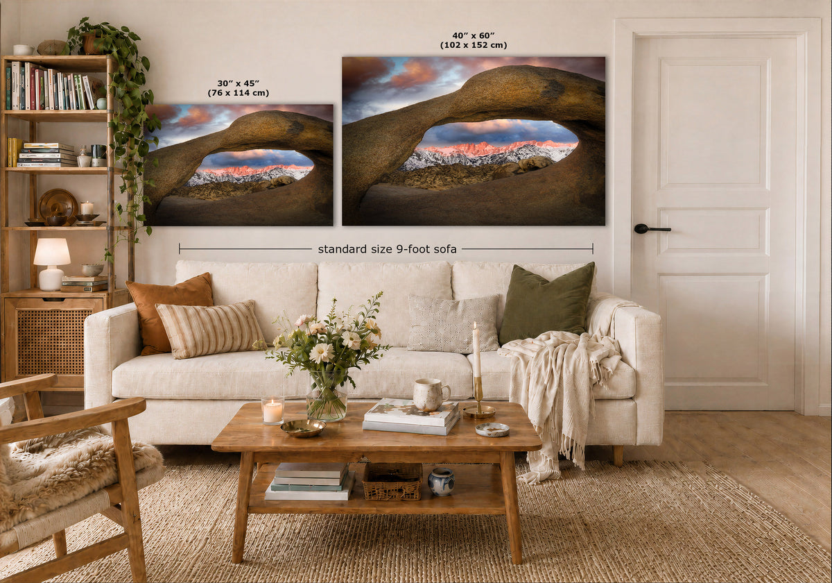 A styled living room showing two wall art prints above a sofa, with size labels overlaid: 30 x 45 inches and 40 x 60 inches. The prints depict a desert arch landscape with warm sunset tones and dark rock arches.