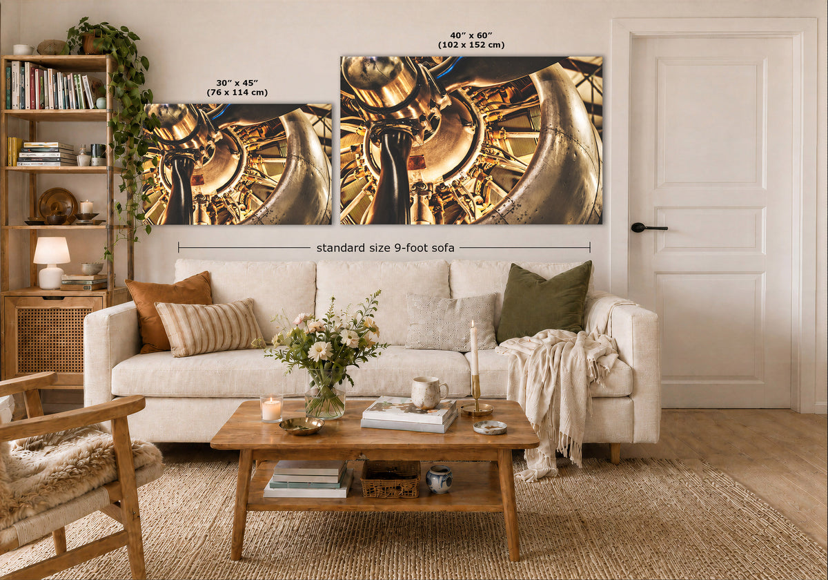 Two wall art prints showing a close-up of a metallic golden mechanical object, displayed above a white sofa in a styled living room. Text labels indicate the dimensions of the prints and a standard size 9-foot sofa.
