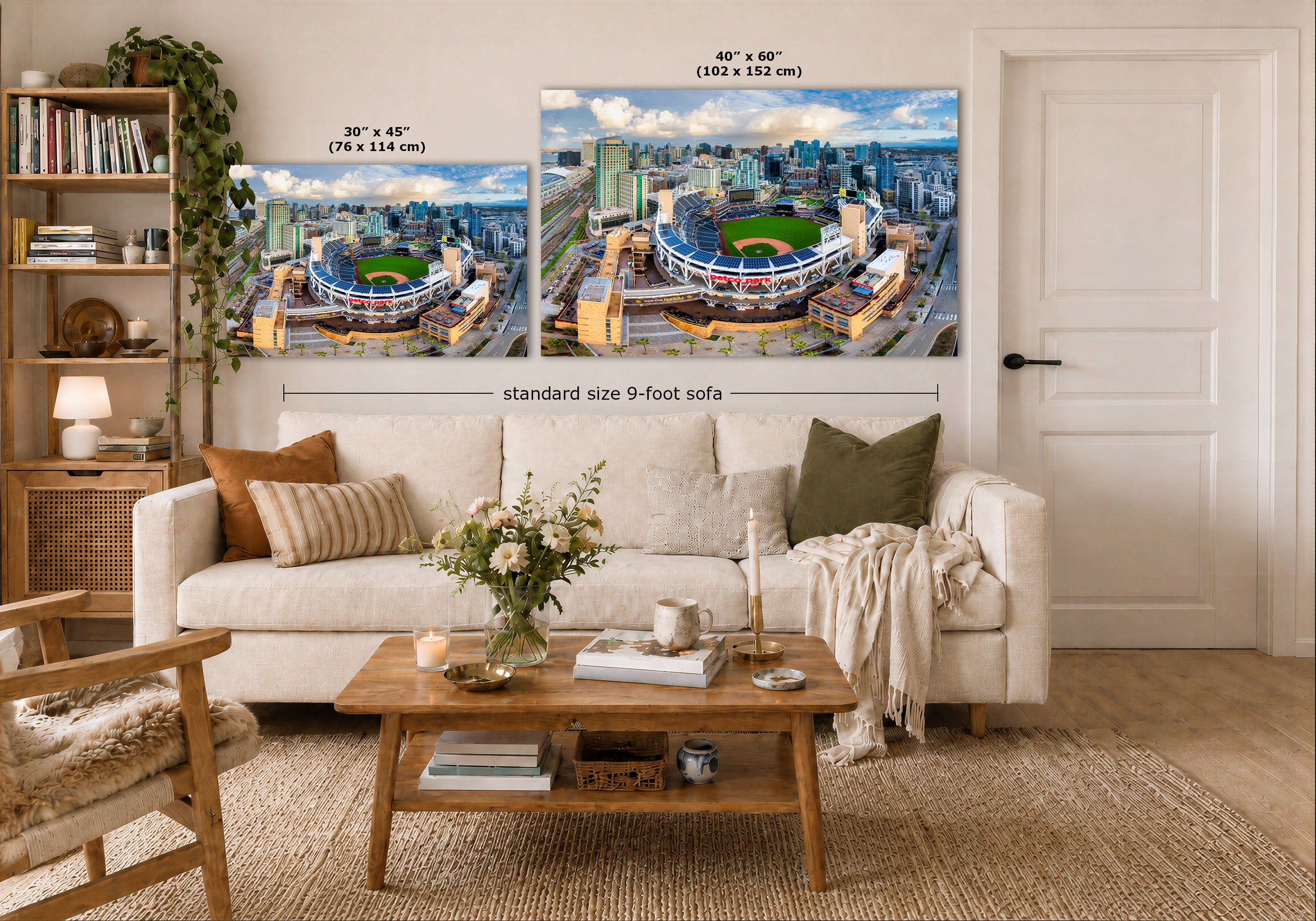 Two large wall art prints showing stadium cityscapes are displayed above a white sofa in a styled living room. The left print is labeled 30 x 45 inches, and the right print is labeled 40 x 60 inches, with a note indicating standard size 9-foot sofa.