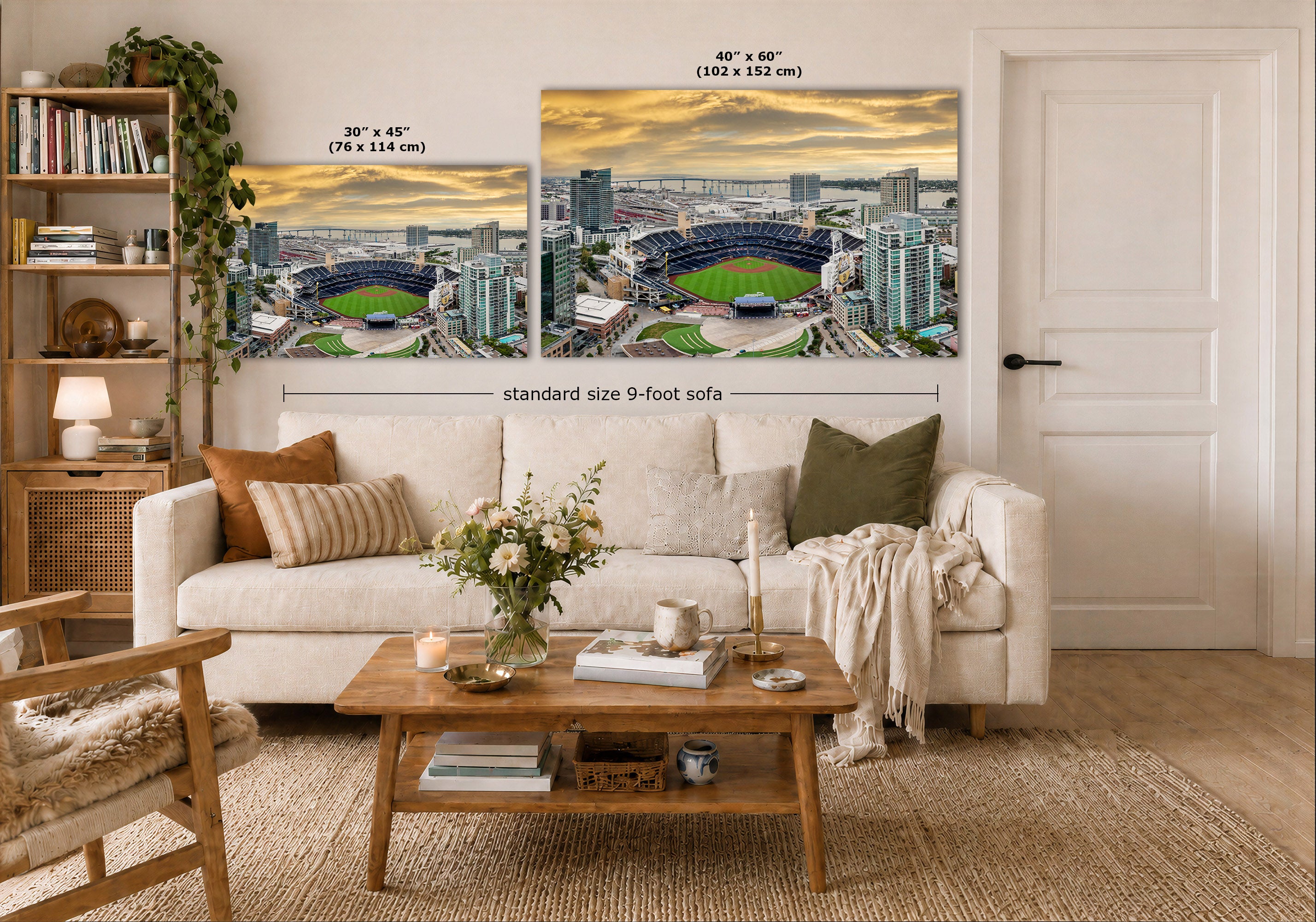 A staged living room showing two large wall art prints above a white sofa. The prints depict a stadium cityscape at sunset, with size labels reading 30 x 45 inches and 40 x 60 inches, plus a dimension line for a standard 9-foot sofa.