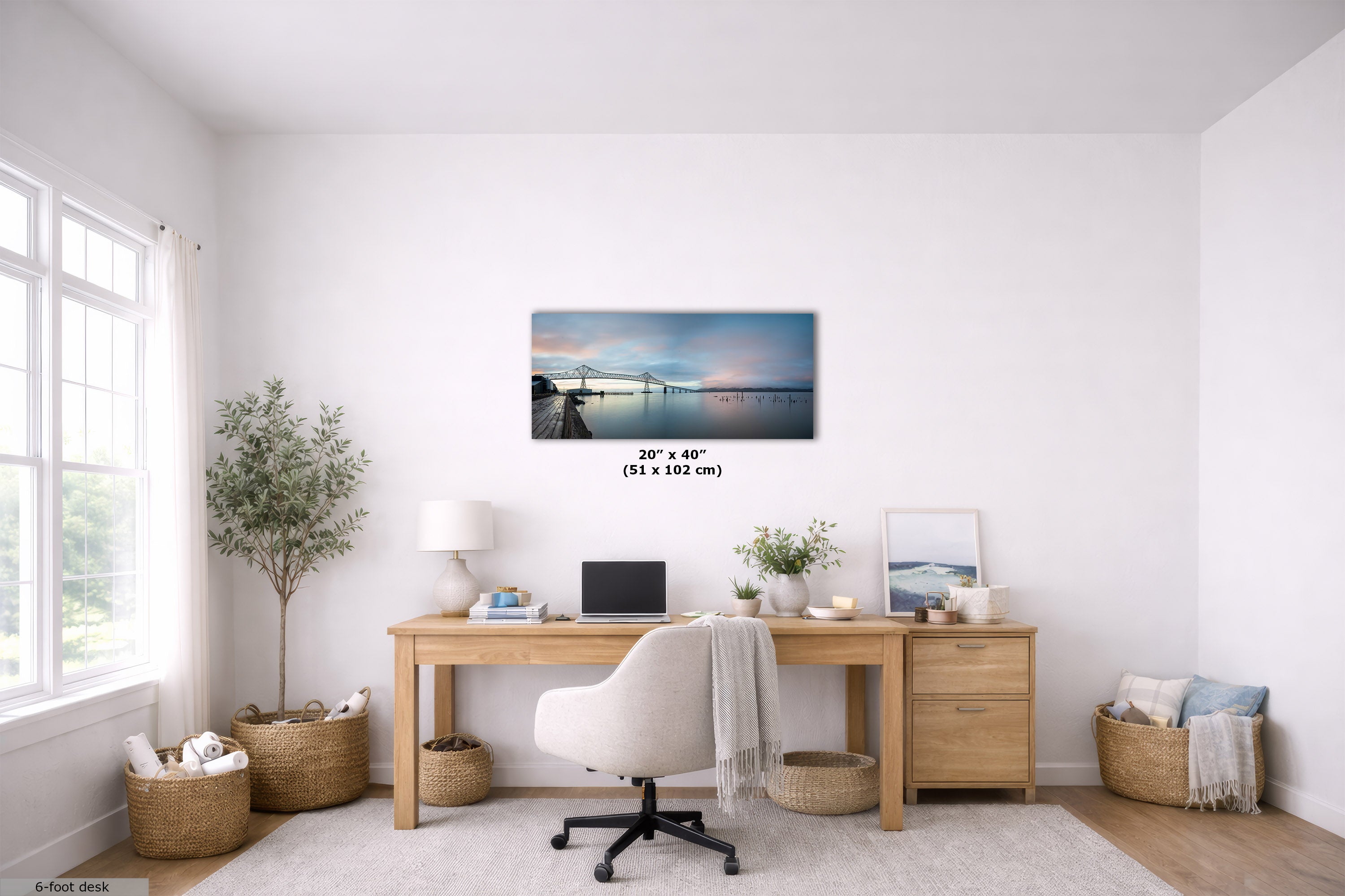 A rectangular wall art print showing a calm waterfront pier scene at dusk, displayed above a wooden desk in a bright, modern home office. The print includes size text reading 24 x 40 inches (51 x 102 cm).