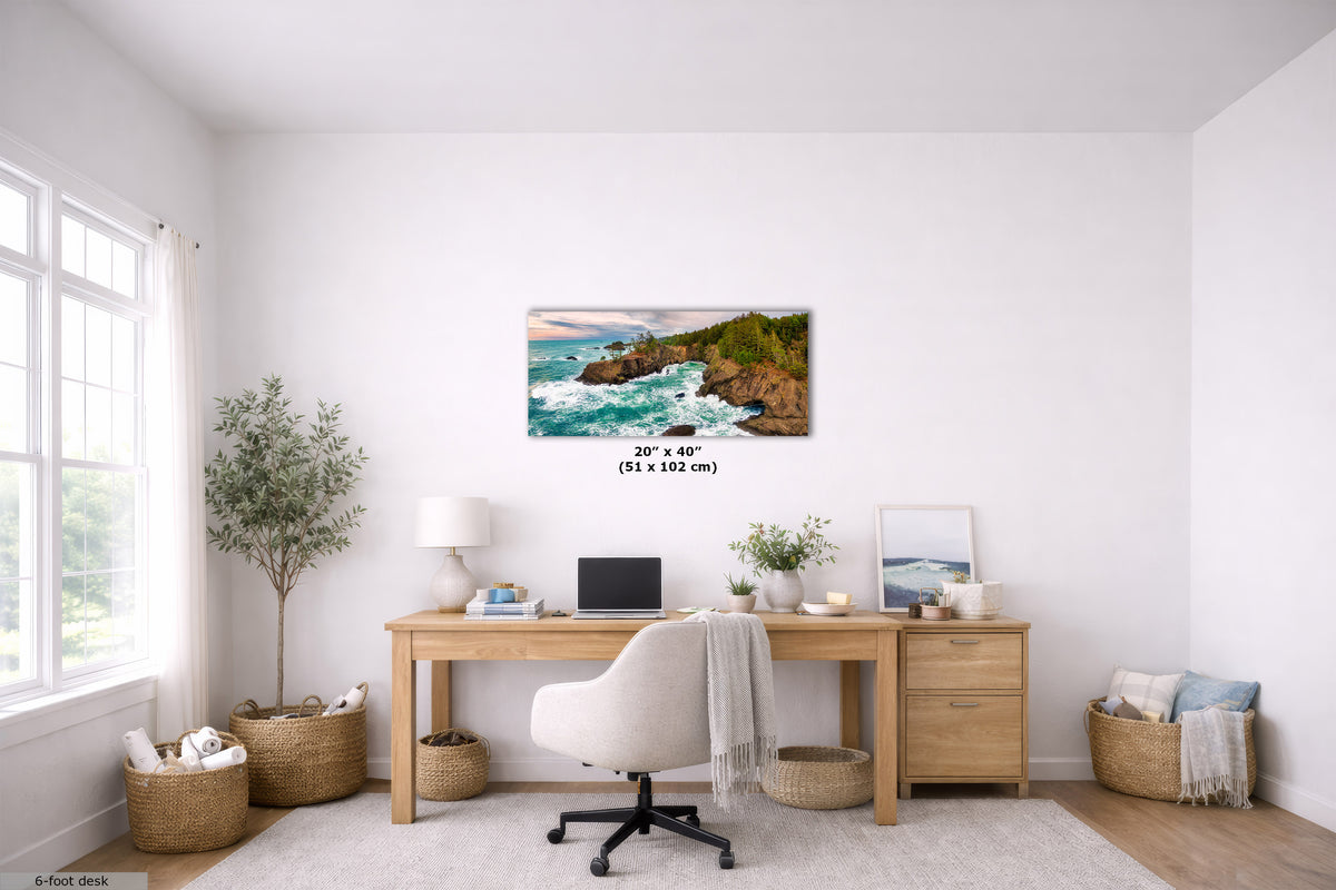 A coastal landscape wall art print hangs above a wooden desk in a bright, modern home office. The print depicts turquoise ocean waves crashing against rocky cliffs with green vegetation.