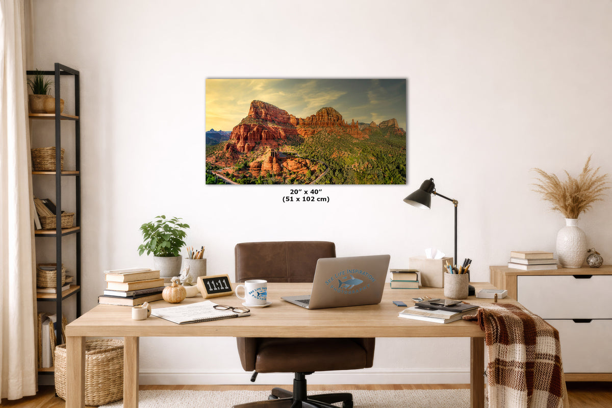 A wall art print depicting a desert canyon landscape with red rock formations and green vegetation, displayed above a wooden desk in a styled home office. The print includes size text reading 20" x 40" (51 x 102 cm) below it.