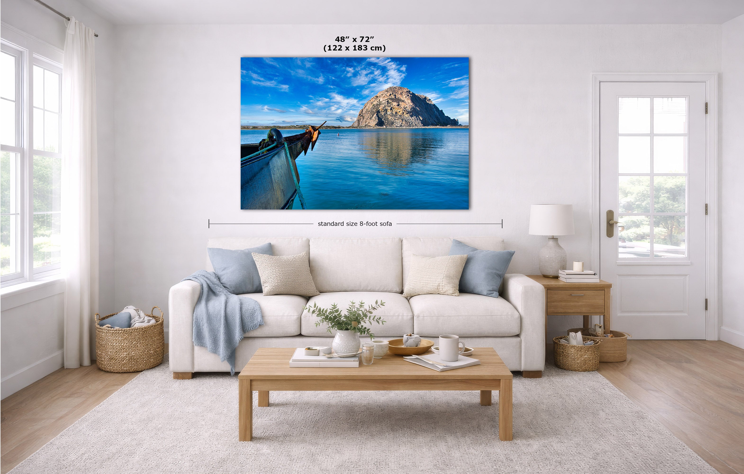 A large rectangular wall art print showing a scenic blue water landscape with a boat and Morro Rock, displayed above a white sofa in a bright living room. Measurement lines and text indicate the print size as 48 x 72 inches.