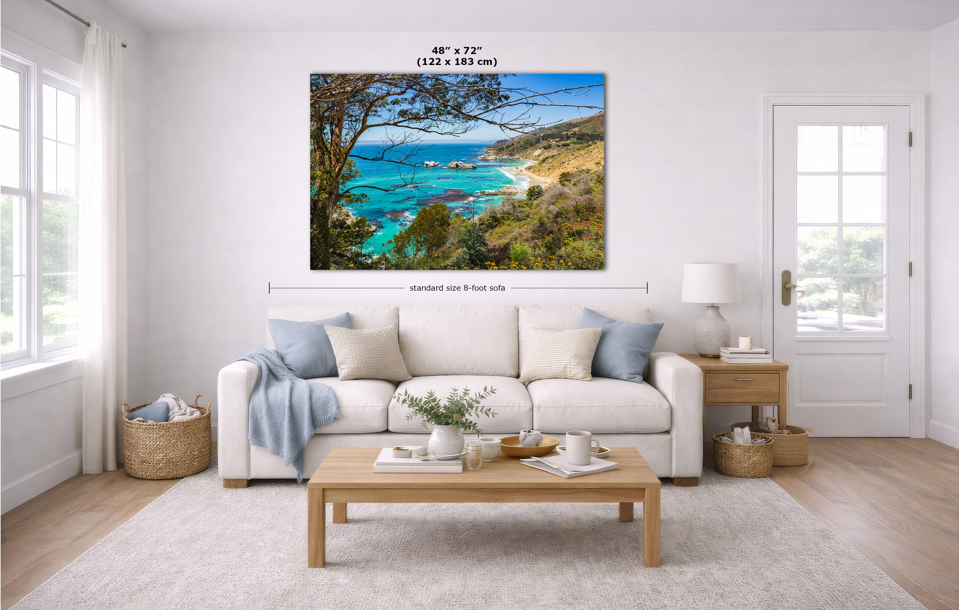 A landscape canvas print of a coastal bay with turquoise water, green hills, and trees, displayed on a white wall in a modern living room mockup with dimension lines and text indicating its size.