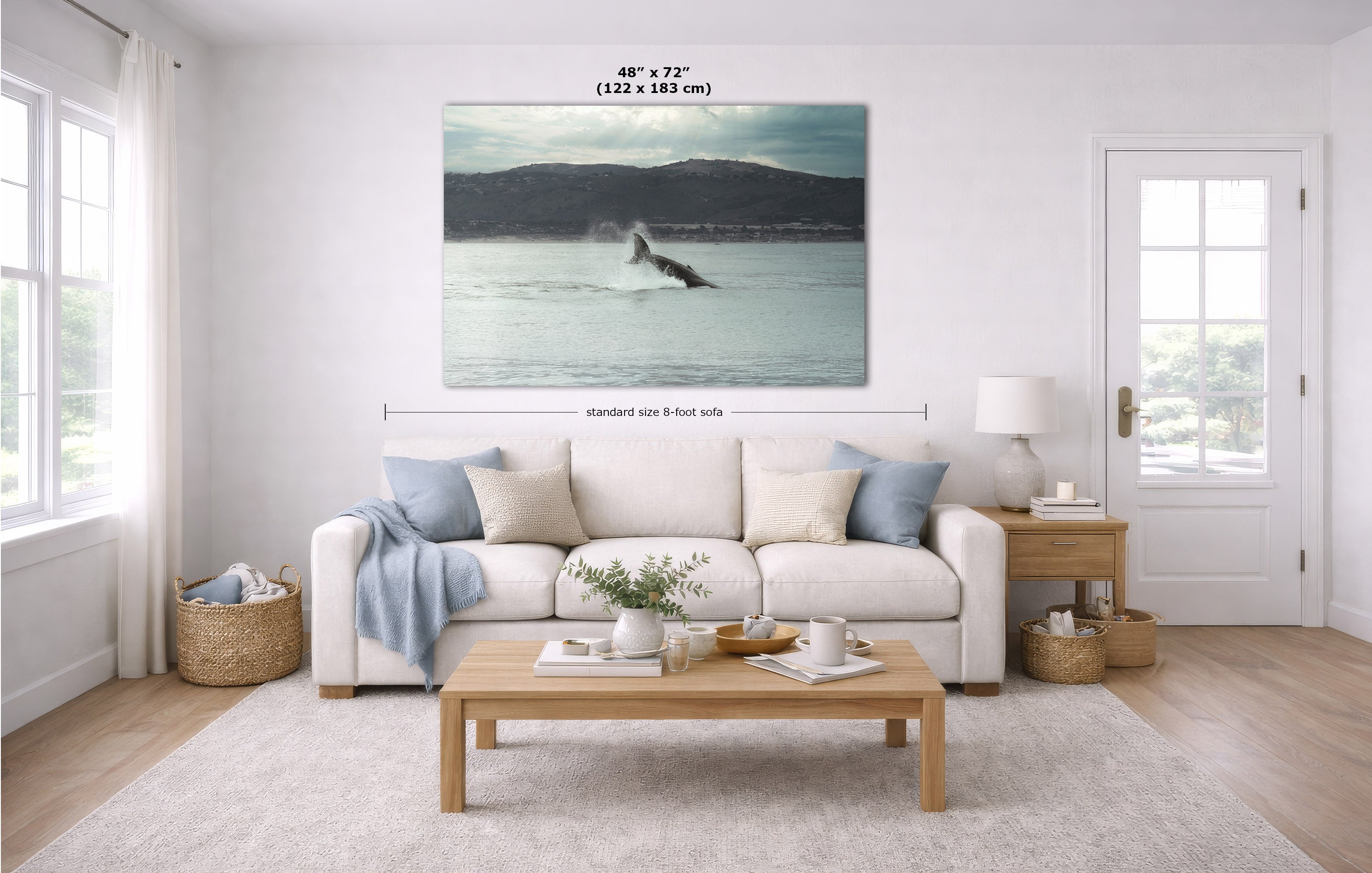 A wall art print showing a whale in a coastal ocean scene, displayed above a white sofa in a bright, modern living room. The image includes dimension lines and text indicating the print size as 48 x 72 inches (122 x 183 m).