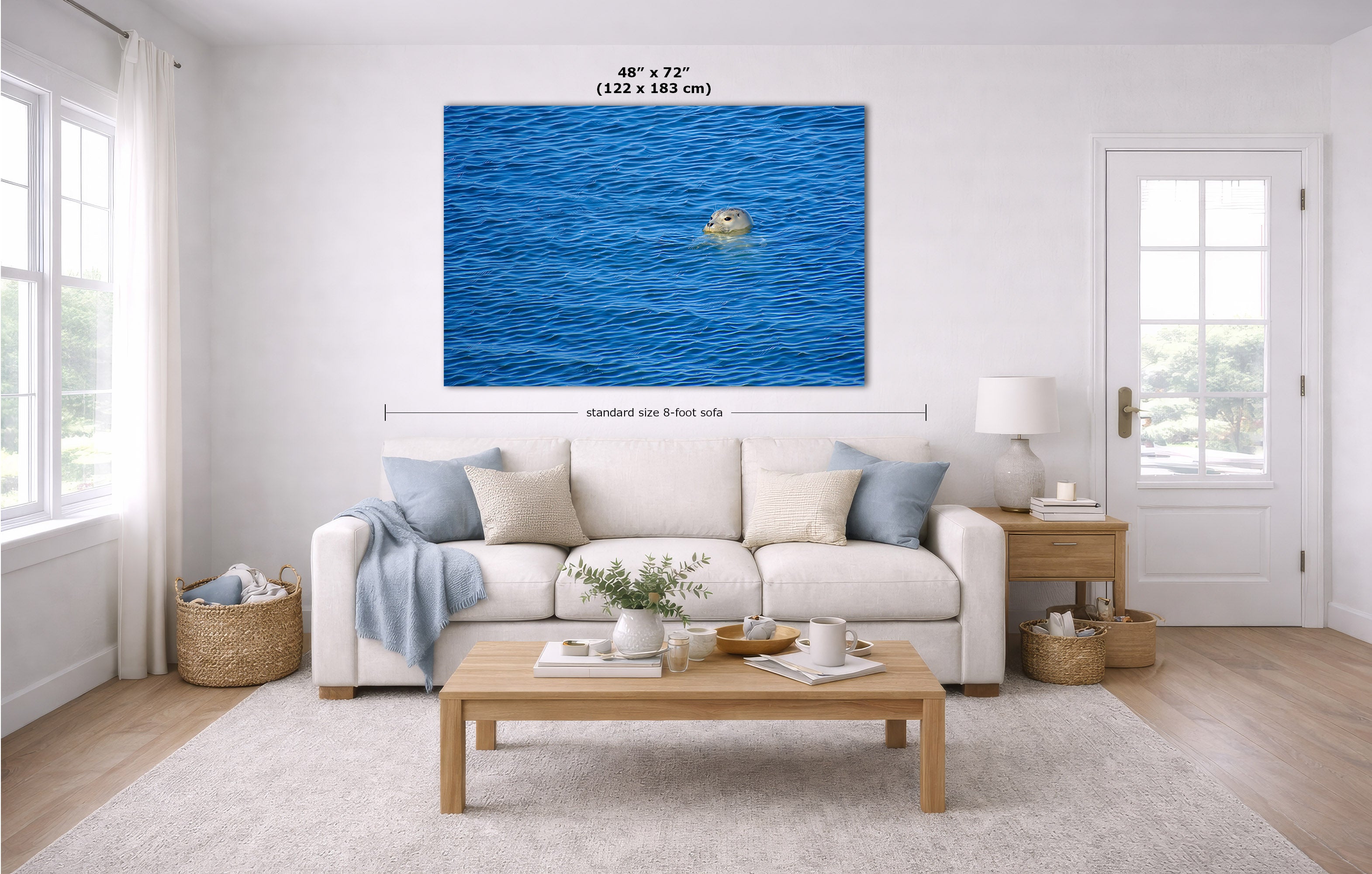 A large canvas wall art print depicting a bright blue ocean, displayed in a modern living room mockup above a white sofa. The image includes dimension lines and text indicating the size is 48" x 72" (122 x 183 cm) and standard size 8 feet per side.