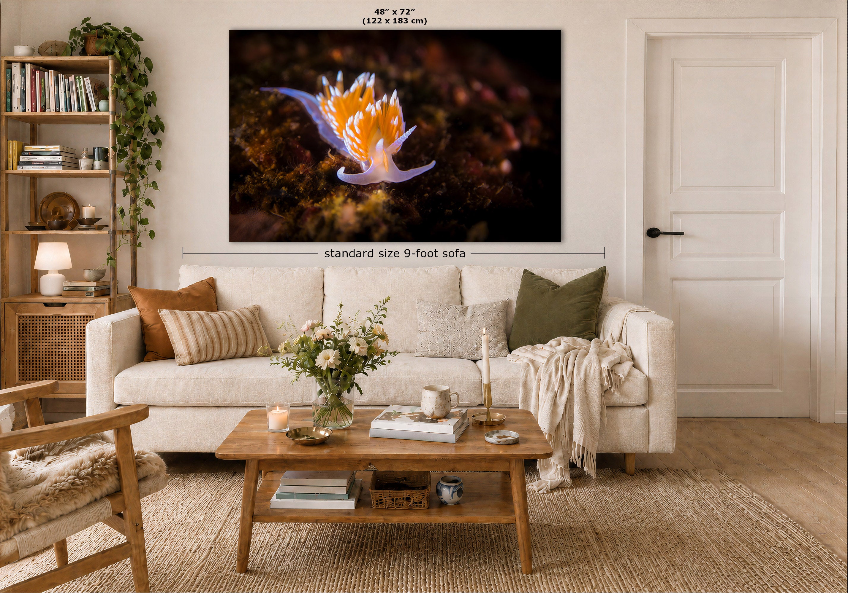 A large framed wall art print showing a close-up of a white and orange nudibranch on a dark background, displayed above a white sofa in a styled living room. The image includes dimension labels indicating 48 x 72 inches and standard size 9-foot sofa.