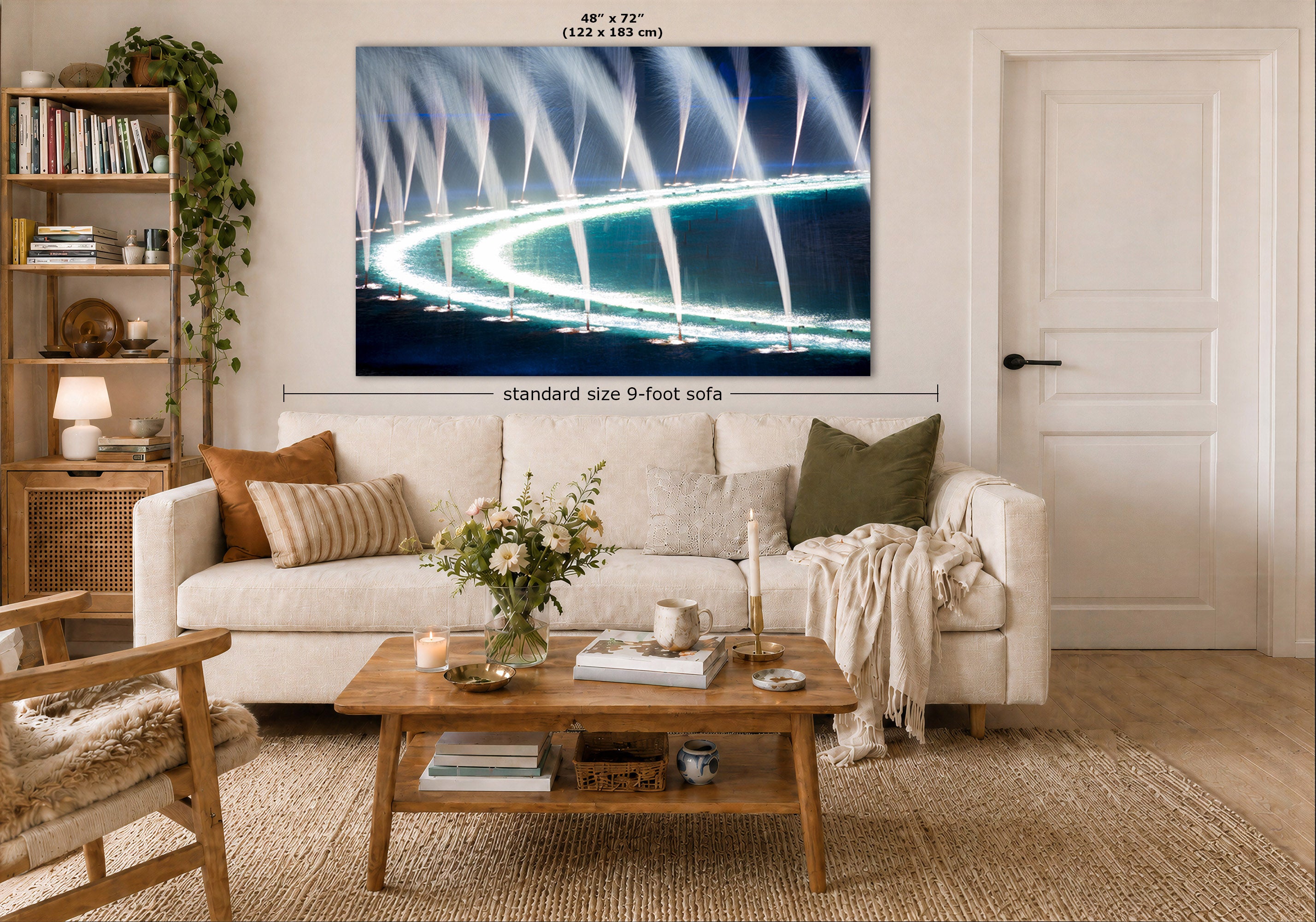 A large rectangular wall art print showing a bright fountain or water fountain scene at night, displayed above a white sofa in a styled living room. Measurement text indicates the print is 48 x 72 inches, and a dimension line notes standard size 9-foot sofa.