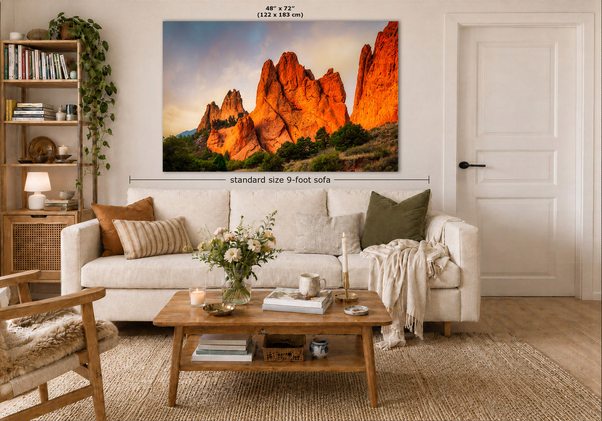 A large wall art print showing a desert rock landscape in warm orange and brown tones, displayed above a white sofa in a styled living room. Measurement text indicates the print is 48 x 72 inches, and a dimension line notes standard size 9-foot sofa placement.