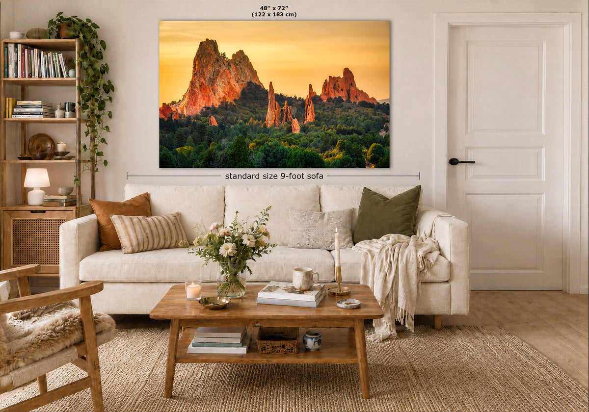 A large wall art print showing a desert rock formation landscape at sunset, displayed above a white sofa in a styled living room. The print includes size labels reading 48" x 72" and a note about standard size 9-foot sofa placement.