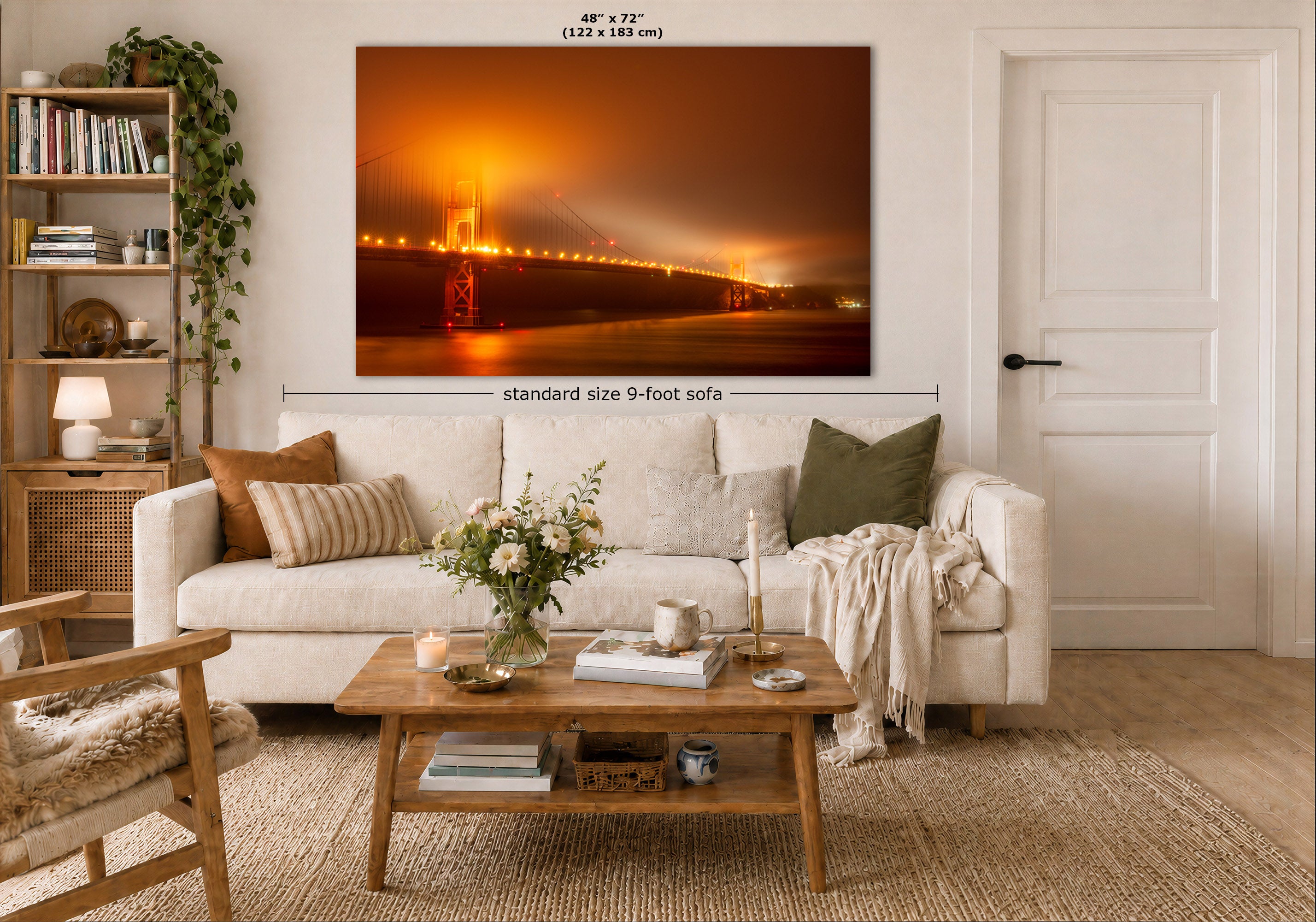 A large wall art print showing a glowing orange Golden Gate Bridge at night, displayed above a white sofa in a styled living room. The image includes dimension labels indicating 48 x 72 inches and a note about standard size 9-foot sofa.