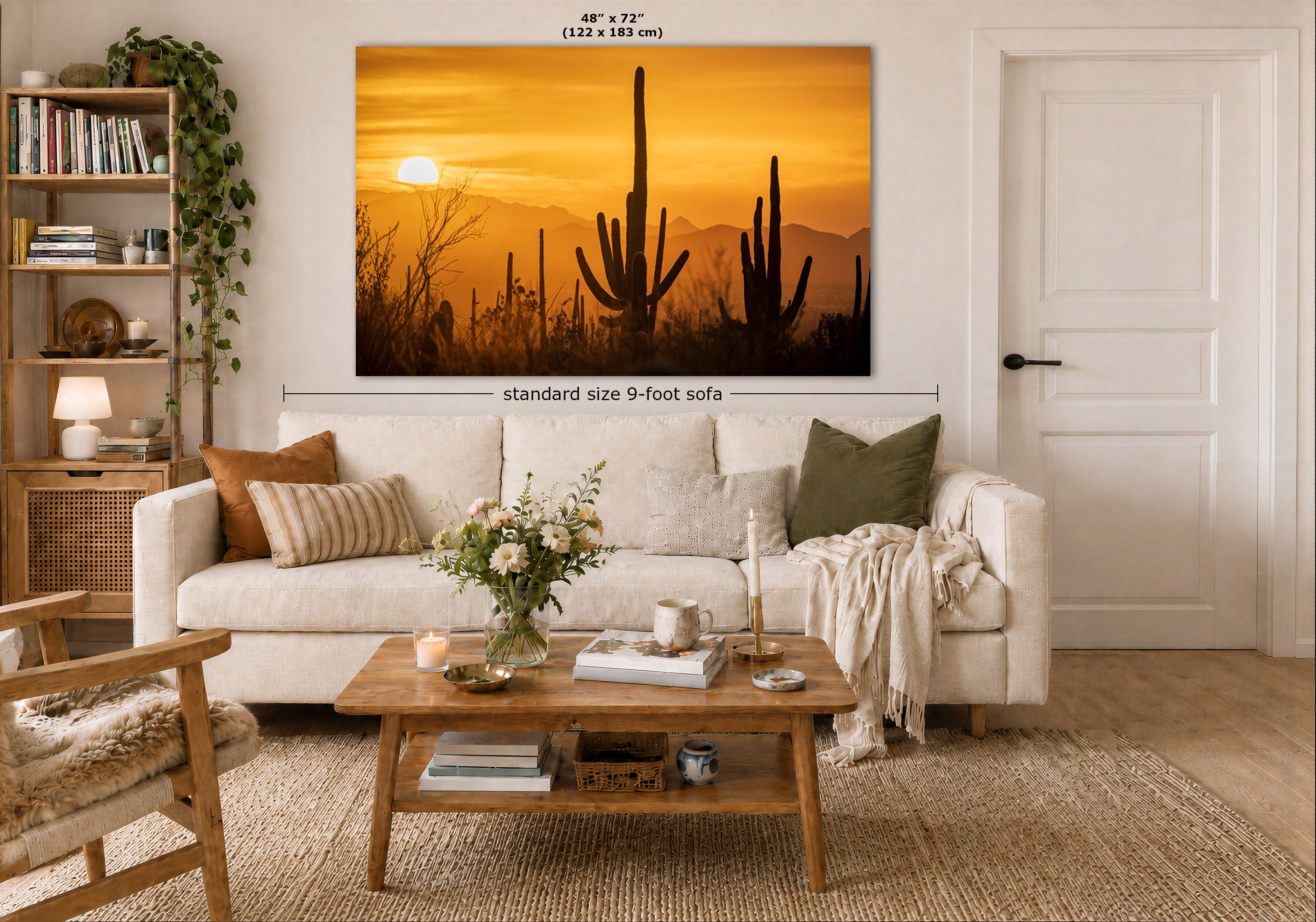 A large wall art print showing a desert sunset with cactus silhouettes, displayed above a white sofa in a styled living room. The print includes dimension labels indicating 48 x 72 inches (122 x 183 cm) and a note reading standard size 9-foot sofa.