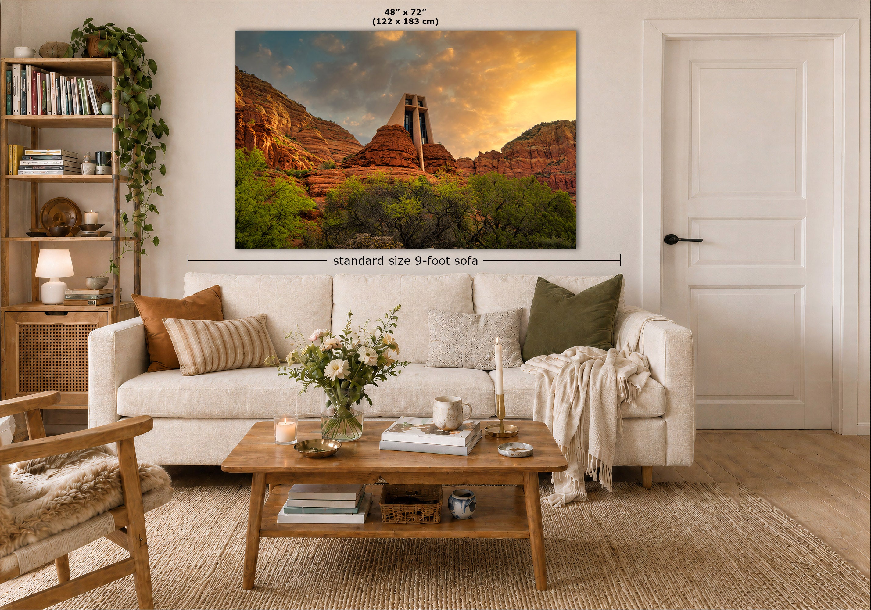 A large wall art print showing a desert canyon landscape with a double-arch rock formation at sunset, displayed above a white sofa in a styled living room. Measurement labels indicate 48 in by 72 in size and standard size 9-foot sofa context.