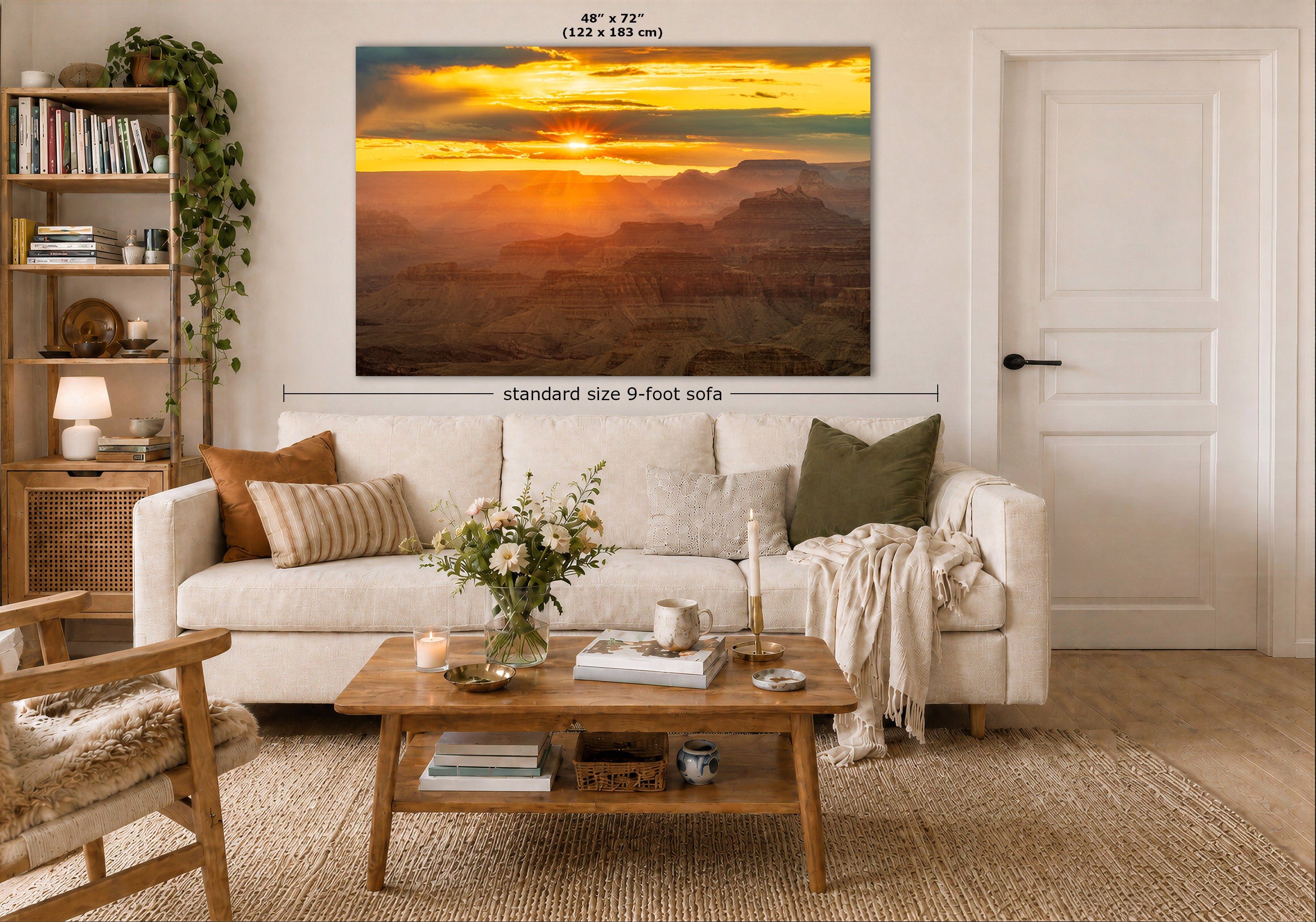 A large wall art print showing a golden sunset over layered canyon mountains, displayed above a white sofa in a styled living room. Measurement labels indicate the print is 48 x 72 inches, with a note about a standard 9-foot sofa below.