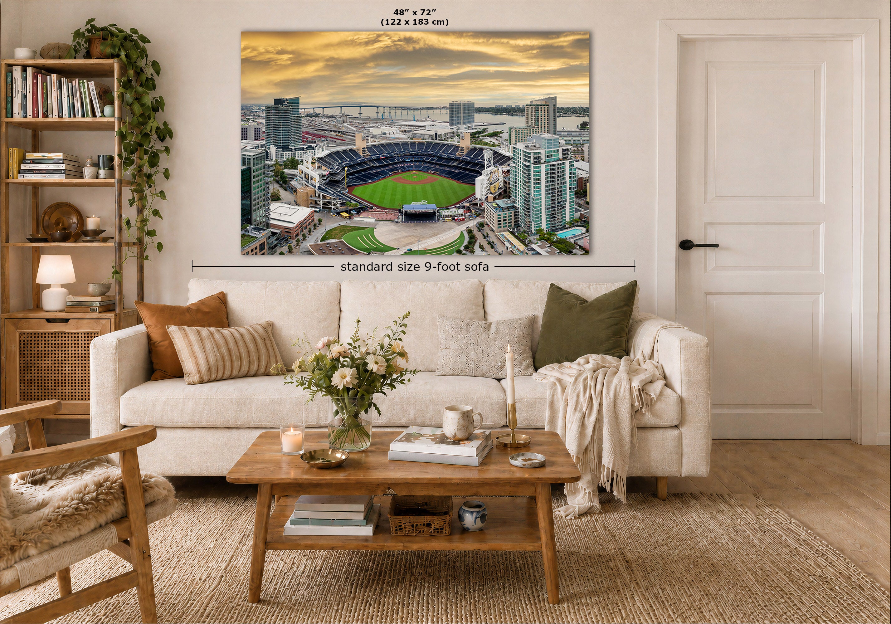 A large rectangular wall art print showing an aerial view of the San Diego Padres Petco Park baseball stadium at sunset, displayed above a white sofa in a styled living room. The print includes size markings reading 48 x 72 inches and 'standard size 9-foot sofa'.