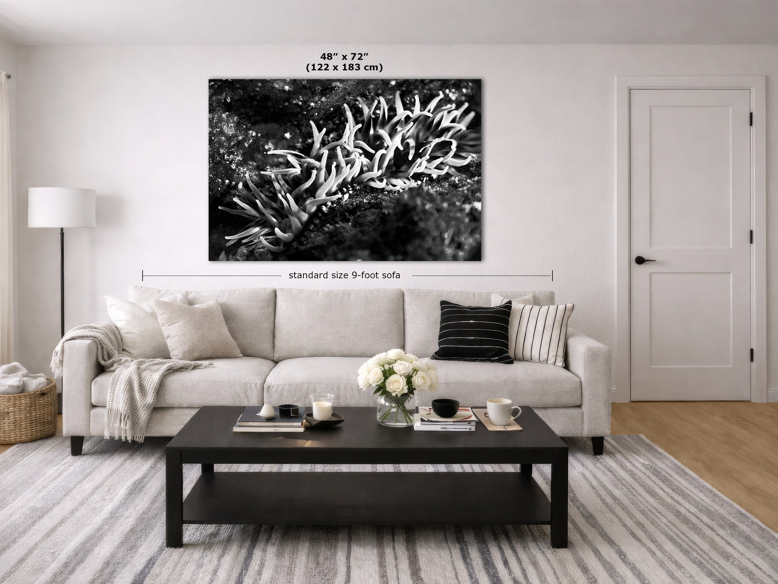 A large black and white canvas wall art print depicting branching coral or sea fan shapes, shown hanging above a light beige sofa in a modern living room. White dimension lines and text indicate the print is 48 x 72 inches (122 x 183 cm) and the sofa is standard size 9 feet.