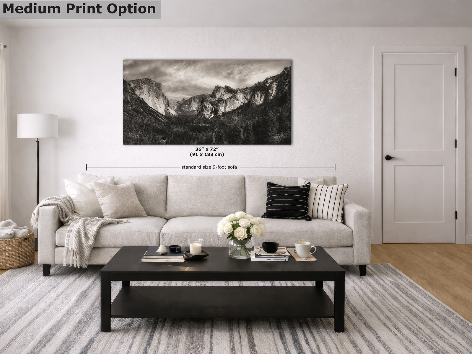 A black-and-white landscape wall art print of Yosemite's Tunnel View and the Sierra Nevada mountain range displayed on a white wall in a modern living room setting above a beige sofa. The image includes dimension markings and a text overlay reading 'Medium Print Option' in the top left corner.