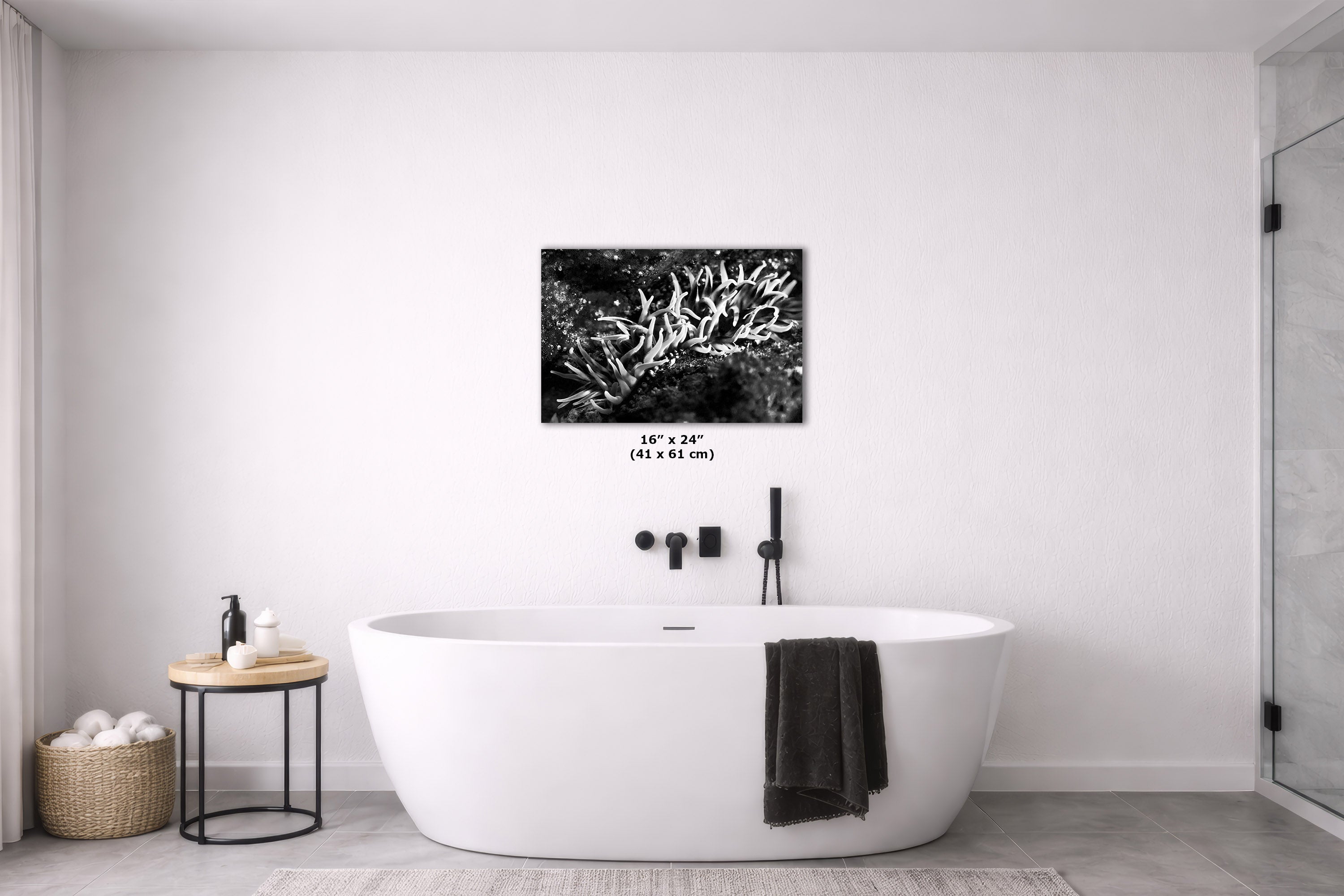 A black and white coral print canvas art piece displayed on a white wall above a modern freestanding bathtub in a minimalist bathroom setting.