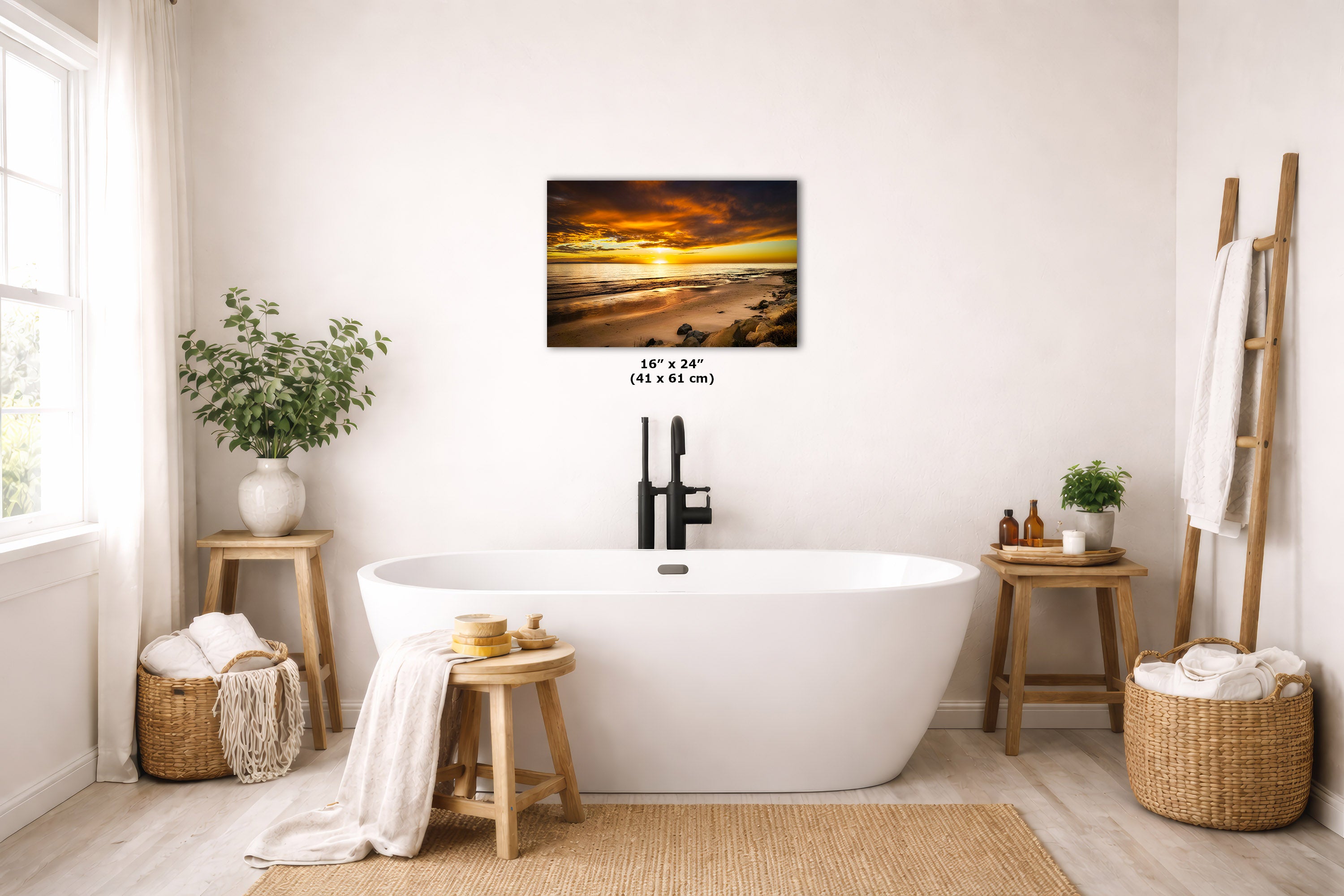 A wall art print depicting a dramatic sunset over water, styled in a bright, modern bathroom above a freestanding white bathtub. The print is shown with its dimensions printed below it.