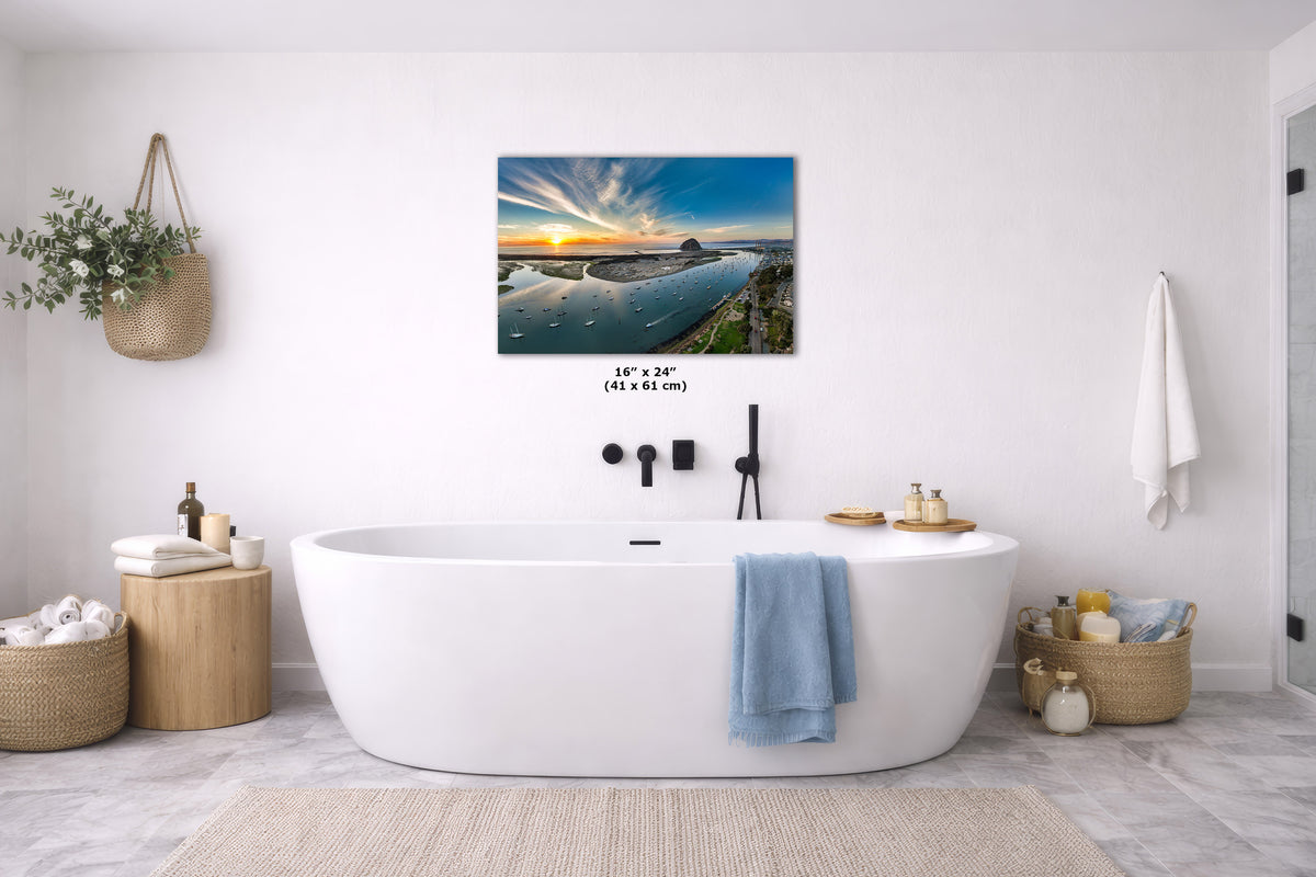 A wall art print showing a coastal sunset over water hangs above a white freestanding bathtub in a bright, modern bathroom. The print is the product being sold, but the image is staged in a real interior environment, so subject type is Lifestyle rather than Scenery or Product/Packaging.