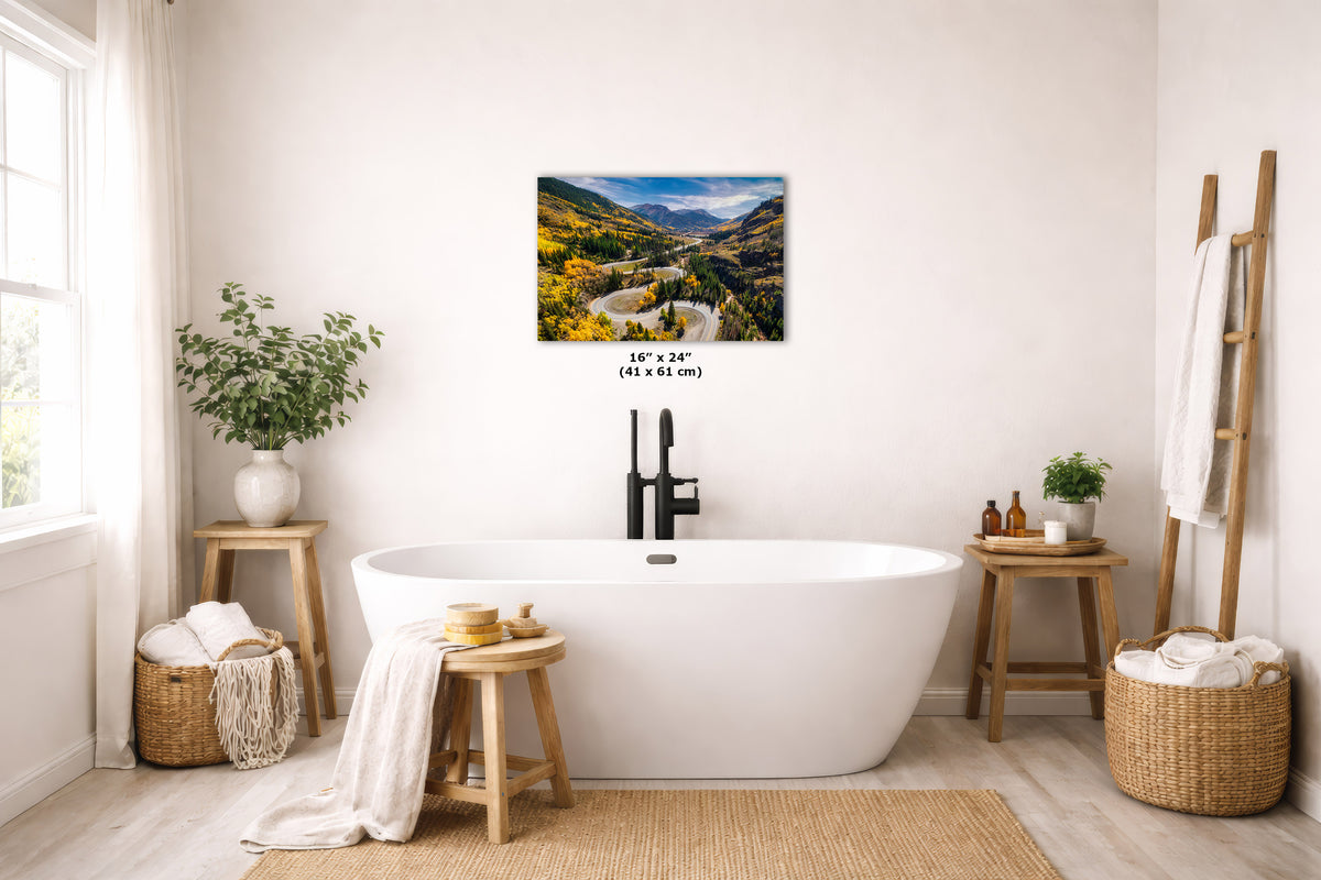 A framed vertical landscape art print depicting giant redwood trees in a forest, displayed on a light beige wall above a white freestanding bathtub in a styled, bright bathroom setting.